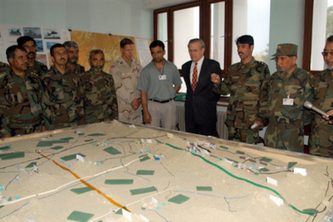 Secretary of Defense Donald H. Rumsfeld receives a briefing at the Kabul Military Training Center in Afghanistan on May 1, 2003. Afghan National Army Brig. Gen. Asifi (in hat) hosted Rumsfeld as he toured the center where Afghan troops are being trained by both U.S. and U.K. military personnel. Rumsfeld is visiting the troops and senior leadership in the Persian Gulf region. 