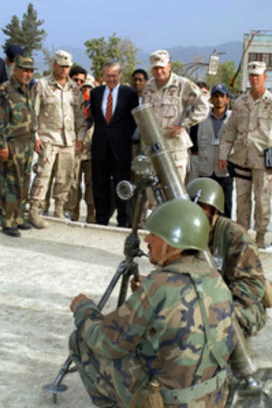 Secretary of Defense Donald H. Rumsfeld watches an Afghan mortar crew at the Kabul Military Training Center in Afghanistan on May 1, 2003. Afghan National Army Brig. Gen. Asifi (in hat) hosted Rumsfeld as he toured the center where Afghan troops are being trained by both U.S. and U.K. military personnel. Rumsfeld is visiting the troops and senior leadership in the Persian Gulf region. 
