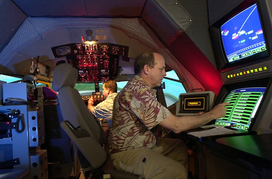 ROYAL AIR FORCE MILDENHALL (AFPN) -- Bruce Golson (front) and Jay Kealhofer demonstrate a simulated emergency aircraft scenario. They run the simulator at the 100th Operations Support Squadron here. The simulator is one of 20 flight simulators that make up the KC-135 Stratotanker aircrew training system located at 14 U.S. and two overseas locations. (U.S. Air Force photo by Tech. Sgt. Michael Morford) 