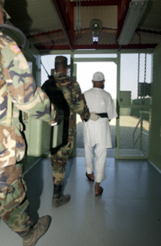 A detainee is escorted to a medium security facility at Guantanamo Bay, Cuba, that houses detainees in a communal living environment allowing greater freedom of movement and group recreation. 