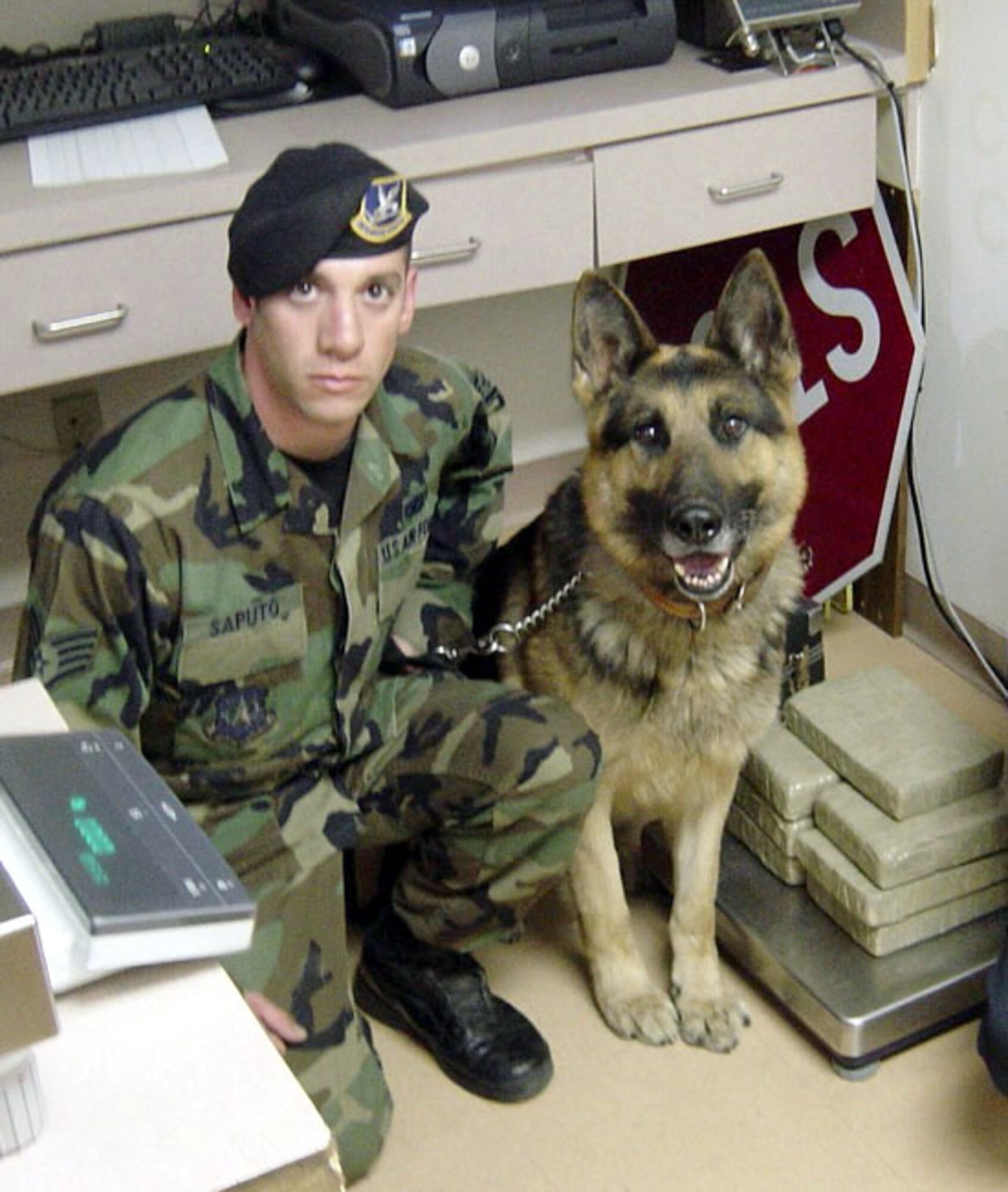 MEXICAN BORDER -- Staff Sgt. Joseph Saputo and his military working dog, Nero, pose with more than 25 pounds of cocaine worth more than $375,000.  The team found the drugs while on temporary duty supporting the U.S. Bureau of Customs and Border Protection here.  They are assigned to the 21st Security Forces Squadron at Peterson Air Force Base, Colo.  (Courtesy photo)