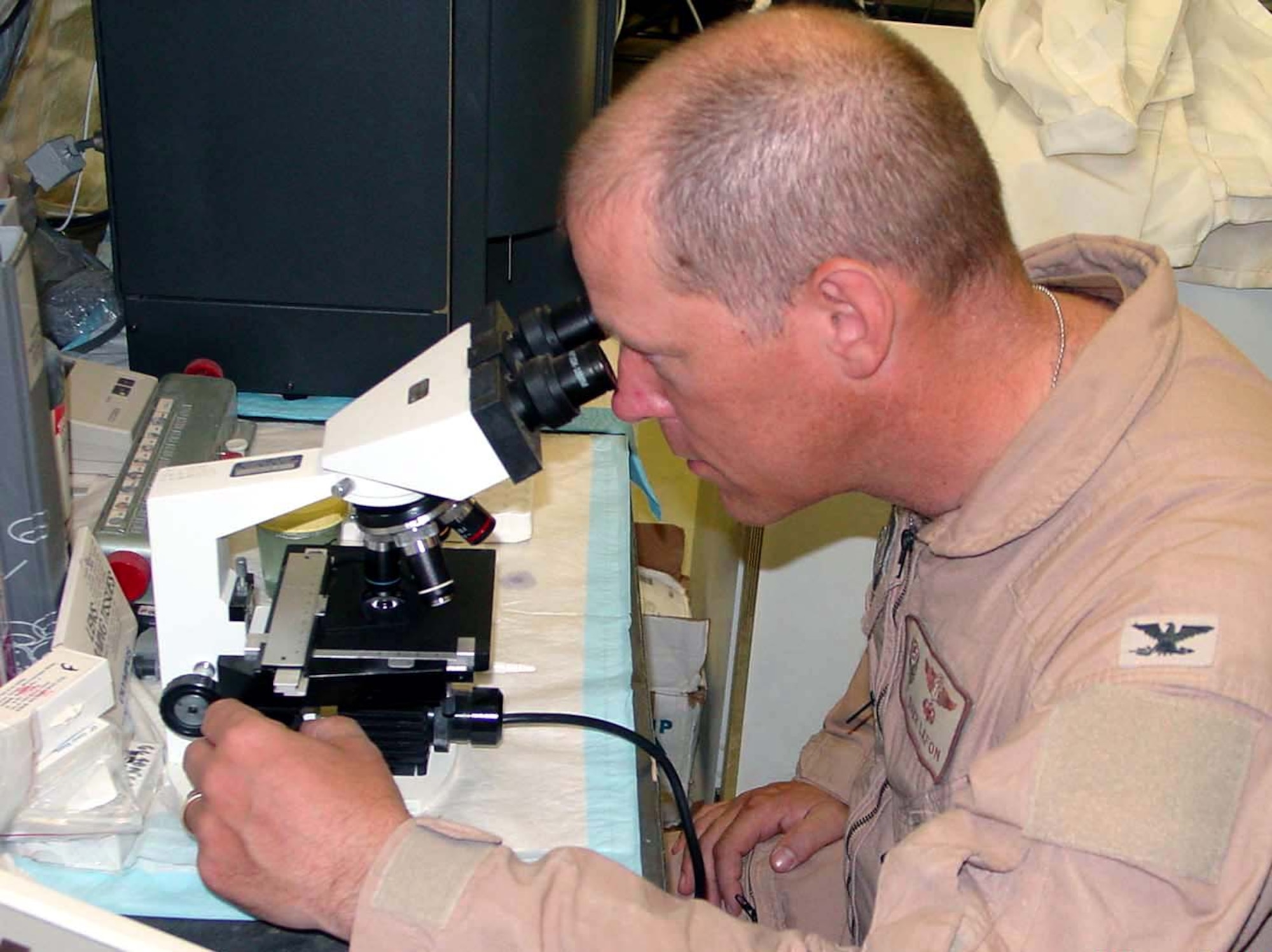 OPERATION IRAQI FREEDOM -- Col. (Dr.) Darr LaFon uses a microscope that is smaller and lighter than previous versions.  This type of equipment dramatically reduces the airlift requirements of deploying medical systems.  LaFon is the commander of the 407th Expeditionary Medical Squadron at Tallil Air Base in southern Iraq.  (U.S. Air Force photo by Maj. Jon Anderson)