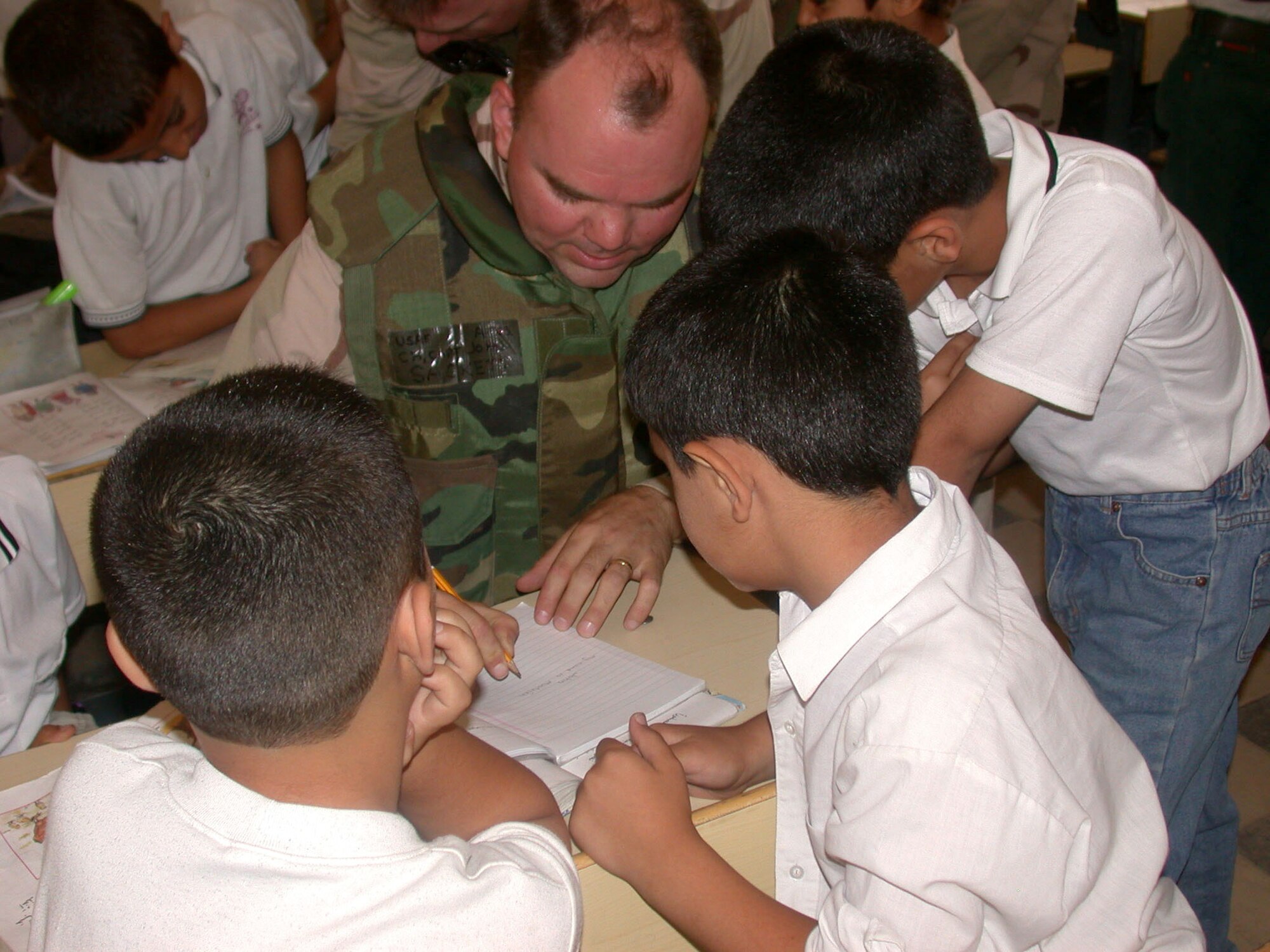 OPERATION IRAQI FREEDOM -- Chaplain (Capt.) John Sackett shows Iraqi pupils how to write their names in English during a recent trip to Baghdad.  Sackett is assigned to the 380th Air Expeditionary Wing at a forward-deployed location.  (U.S. Air Force photo by Capt. David P. Lester)
