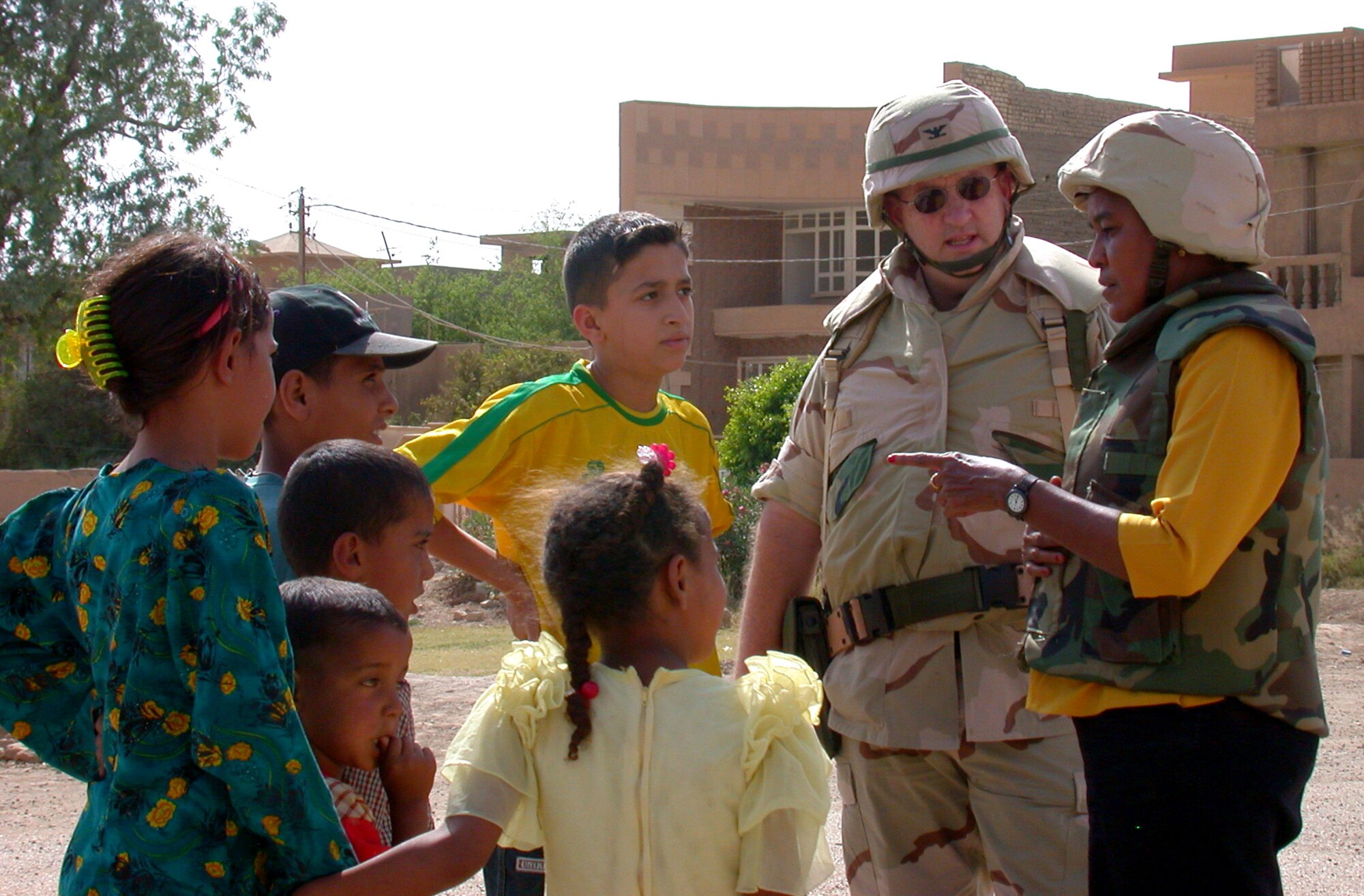 OPERATION IRAQI FREEDOM -- Awatif M. Sidahmed (right) translates for Iraqi school children and Col. Scott Harrison during their recent humanitarian mission in Baghdad.  Sidahmed is a linguist assigned to the 380th Air Expeditionary Wing.  Harris is the former vice commander of the unit.  (U.S. Air Force photo by Capt. David P. Lester)