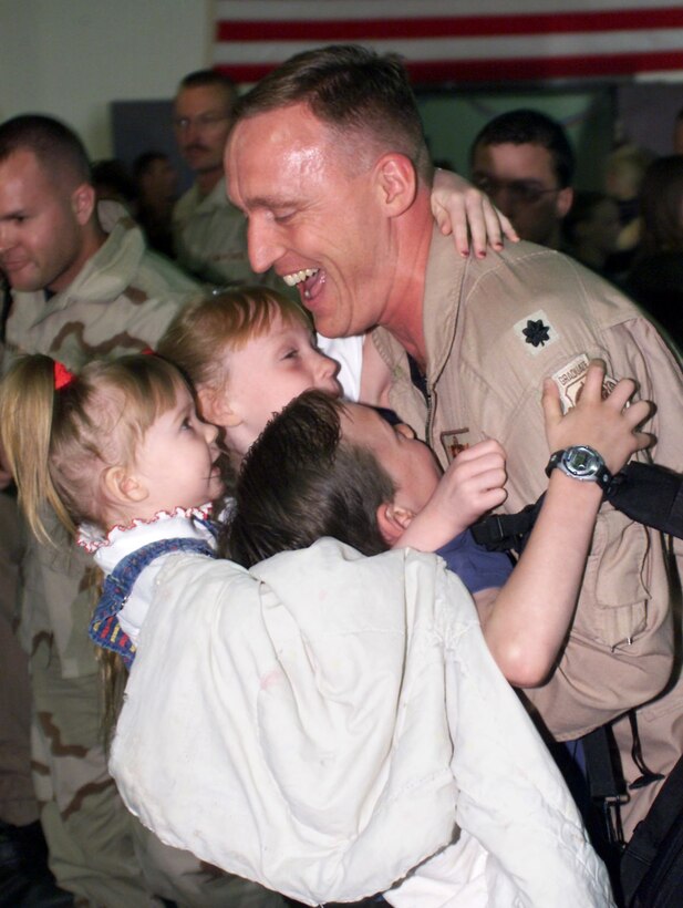 ELLSWORTH AIR FORCE BASE, S.D. -- Lt. Col. Mark Schlichte, the 28th Bomb Wing chief of safety here, hugs his children (left to right), Mary Kate, Meghan and Mark, after his return home May 21.  Approximately 280 airmen returned here from deployments supporting operations Enduring Freedom and Iraqi Freedom.  (U.S. Air Force photo by Airman 1st Class Karah McNeill)