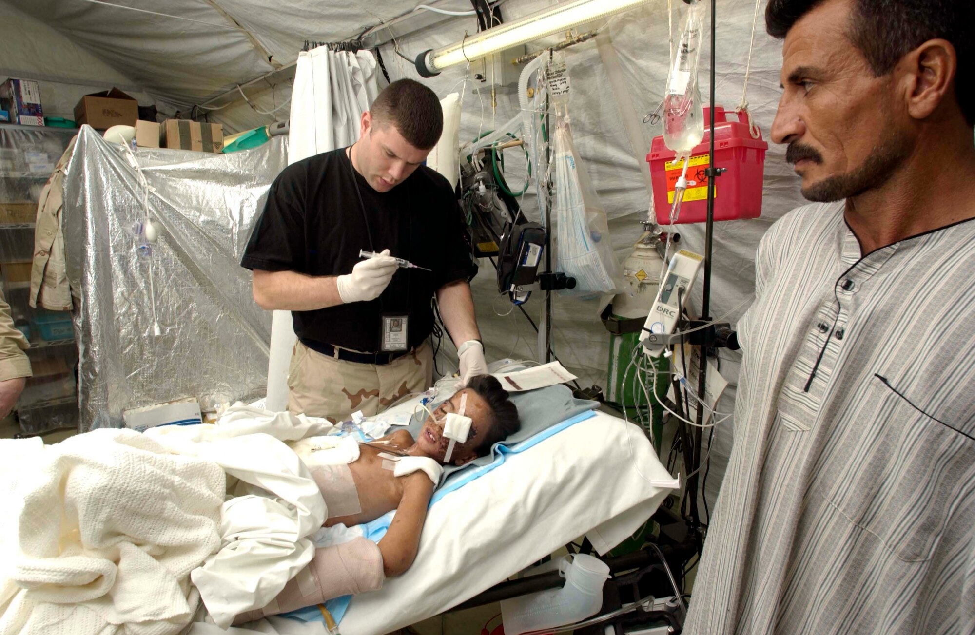 TALLIL AIR BASE, Iraq -- Capt. James Smith prepares medication for 9-year-old Saleh Kahlaf while his father, Raheem Kahlaf, watches.  Saleh was critically injured by a land mine near his school in Al Nasiriyah and had been cared for by 332nd Expeditionary Medical Squadron airmen until his aeromedical evacuation mission to the United States.  The boy arrived at Children's Hospital and Research Center in Oakland, Calif., on Nov. 10.  Smith is assigned to the 332nd EMEDS hospital here.  (U.S. Air Force photo by Master Sgt. Lance Cheung)