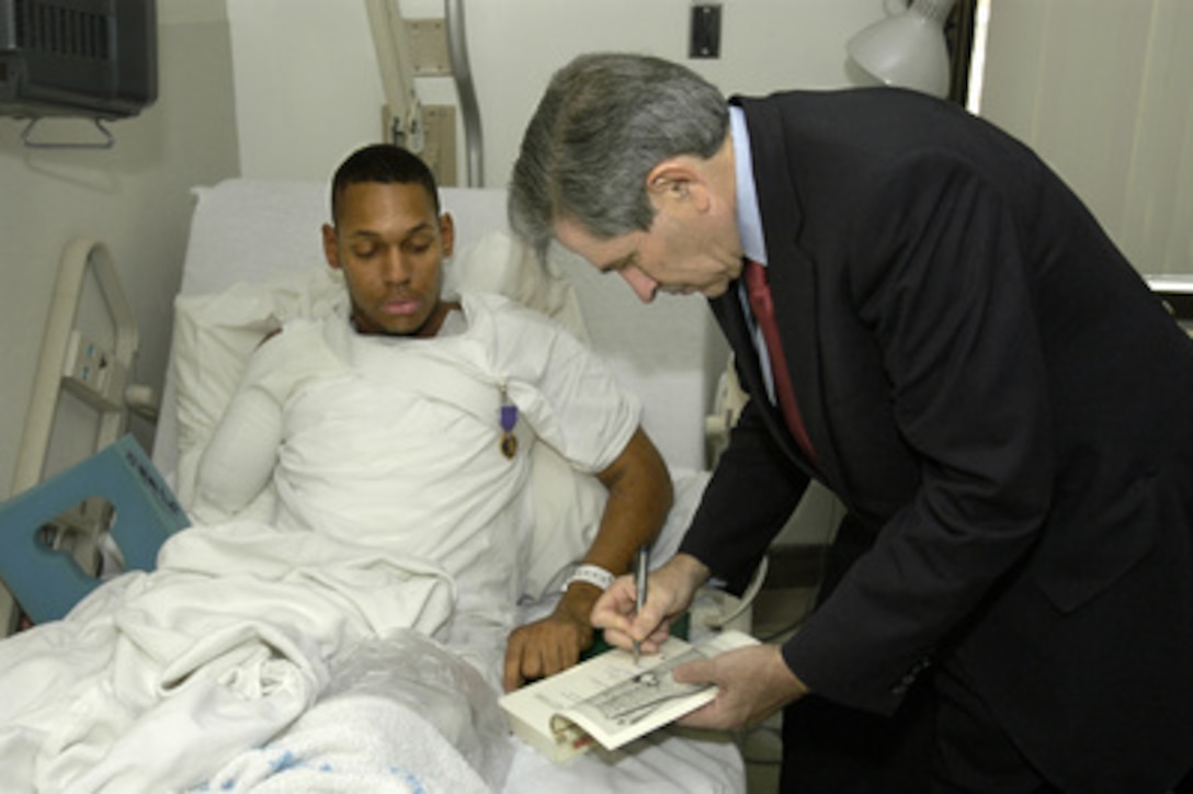 Deputy Secretary of Defense Paul Wolfowitz autographs a book by Andrew Carroll entitled "War Letters" for Army Spc. Alan M. Seals at Walter Reed Army Medical Center in Washington, D.C., on Nov. 11, 2003. Wolfowitz presented Seals the Purple Heart medal in recognition of the wounds he received in combat. Wolfowitz visited with wounded soldiers from Iraq and Afghanistan before joining President Bush at Arlington National Cemetery for the traditional Veterans Day observances. 