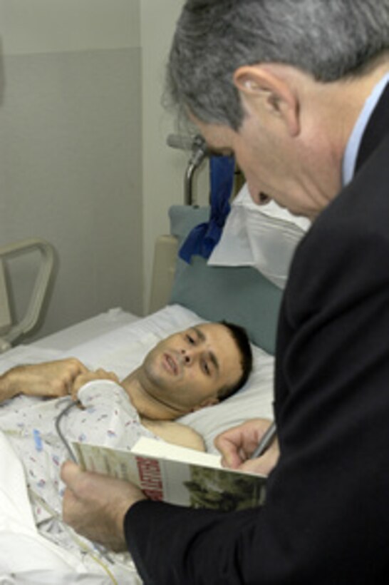 Army Sgt. Shawn Monroe looks on as Deputy Secretary of Defense Paul Wolfowitz adds an inscription to that of author Andrew Carroll in a copy of the book "War Letters" at Walter Reed Army Medical Center in Washington, D.C., on Nov. 11, 2003. Wolfowitz visited with wounded soldiers from Iraq and Afghanistan before joining President Bush at Arlington National Cemetery for the traditional Veterans Day observances. "War Letters" is a compilation of letters home from American service men and women in all our wars. 