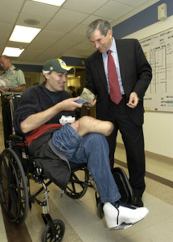 Deputy Secretary of Defense Paul Wolfowitz suggests that Green Bay Packers fan Sgt. Michael Cain might prefer to wear a Department of Defense baseball cap after the recent Monday-night loss of Green Bay to the Philadelphia Eagles. Cain is recovering at Walter Reed Army Medical Center in Washington, D.C., from serious wounds received while serving in Iraq. Wolfowitz was in the hospital on Nov. 11, 2003, to visit with some of the wounded soldiers before joining President Bush at Arlington National Cemetery for the traditional Veterans Day observances. 