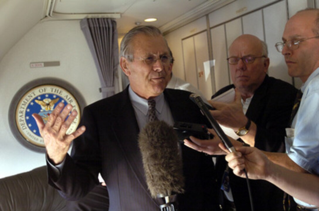 Secretary of Defense Donald H. Rumsfeld responds to a reporter's question during an informal press briefing while en route to Tokyo to meet with Japan's Prime Minister Junichiro Koizumi on Nov. 14, 2003. Reuter's reporter Charles Aldinger (center) and New York Times reporter Thom Shanker are accompanying Rumsfeld as he travels to Guam, Japan and South Korea to meet with U.S. military forces and the local military and civilian leadership. 