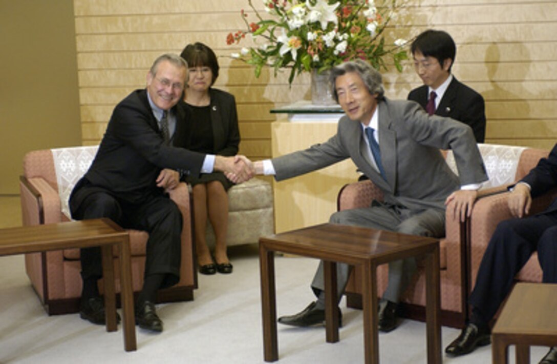 Secretary of Defense Donald H. Rumsfeld and Prime Minister Junichiro Koizumi stretch to shake hands for the photographers as they meet in Tokyo, Japan, on Nov. 14, 2003. Rumsfeld is in Japan to meet with U.S. military forces and local officials. 
