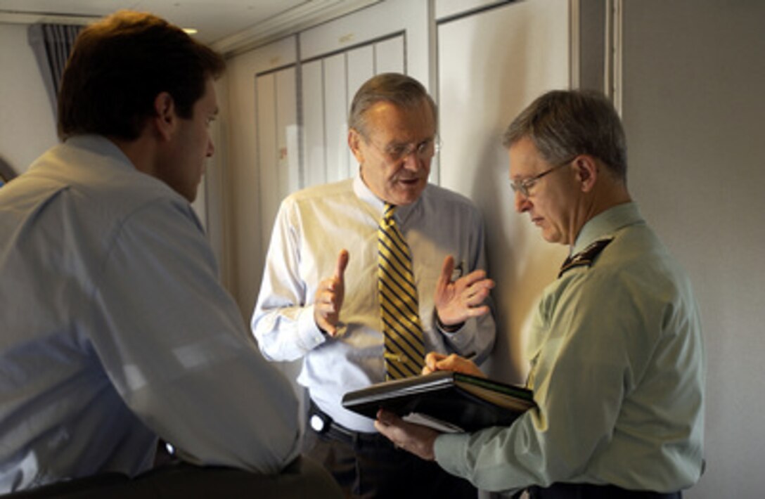 Secretary of Defense Donald H. Rumsfeld (center) speaks with Army Lt. Gen. John Craddock (right) and Acting Assistant Secretary of Defense for Public Affairs Lawrence Di Rita (left) while en route to Okinawa, Japan, on Nov. 16, 2003. Rumsfeld is traveling to Guam, Japan and South Korea to meet with U.S. military forces and the local military and civilian leadership. Craddock is the senior military assistant to the Secretary of Defense. 