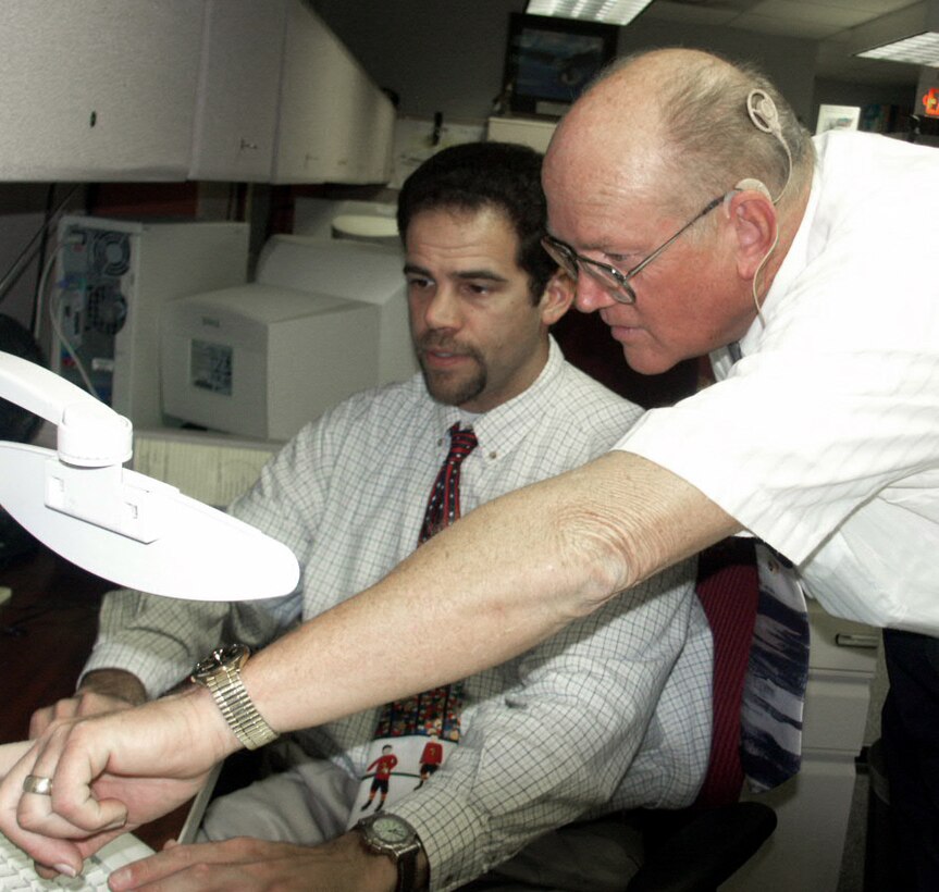 LACKLAND AIR FORC BASE, Texas -- Retired Maj. Robert Graves (right) discusses simulation technology with Steven Alagona, course manager for security-forces training here.  Graves received a cochlear implant at Wilford Hall Medical Center on Jan. 8.  He is the chief of the 342nd Training Squadron's training development element of security-forces training.  (U.S. Air Force photo by Susan Campbell)