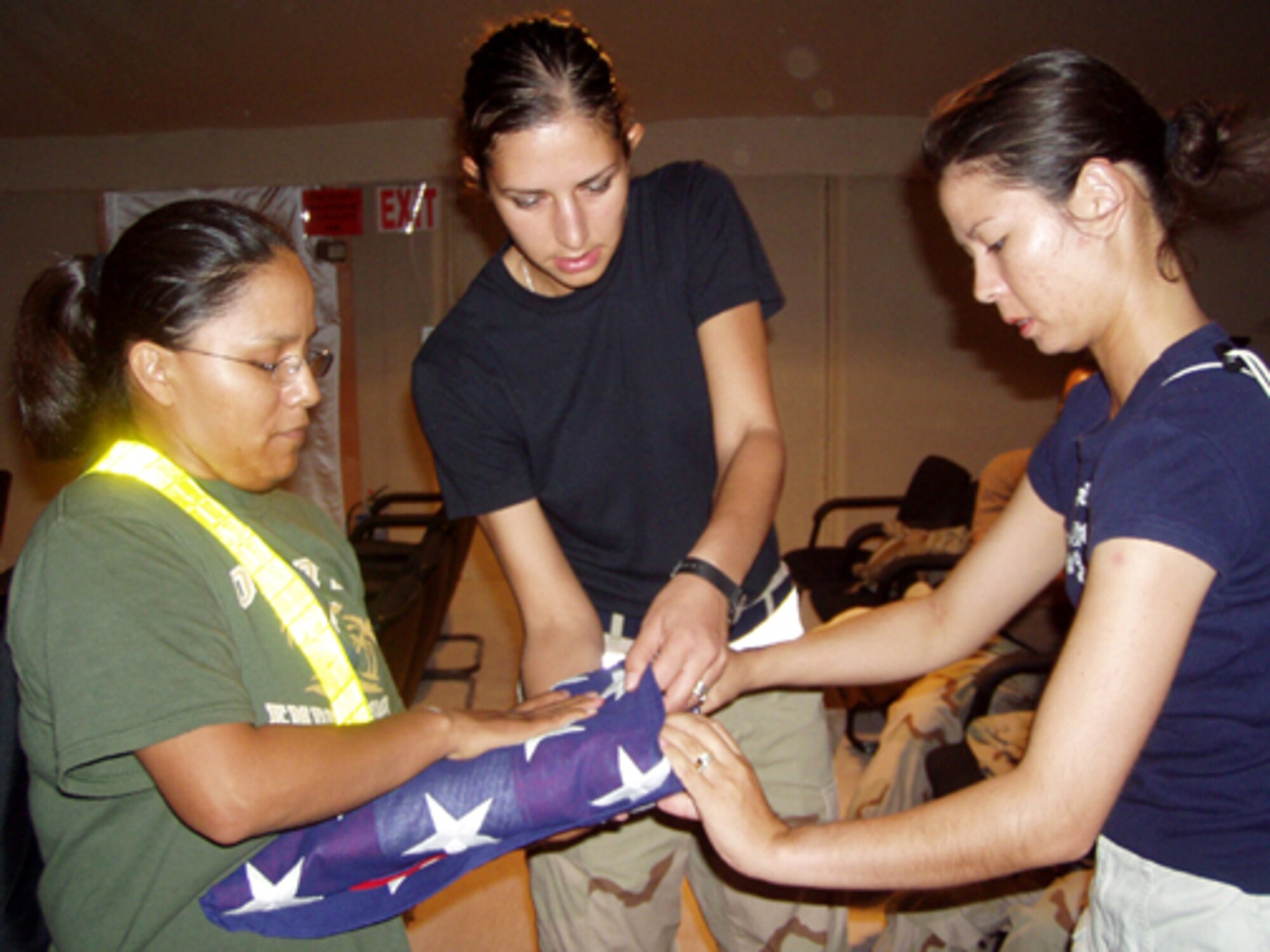 AL UDEID AIR BASE, Qatar -- Senior Airman Ivelina Konstantinova (center) helps Staff Sgt. Leandra Lee (left) and Airman 1st Class Ann Flaherty with flag-folding techniques during base honor guard practice here Oct. 1.  (U.S. Air Force photo by Master Sgt. William J. Sharp)
