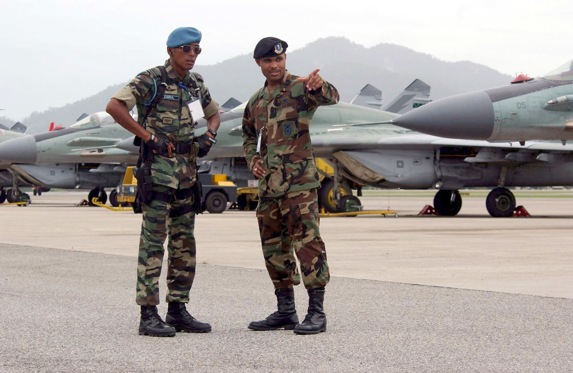 LANGKAWI, Malaysia -- First Lt. Jalaal Green (right) and Capt. Ibrahim Hisham Zairul discuss flightline security during the Langkawi International Maritime and Aerospace 2003 exhibition here.  Green is from the 613th Contingency Response Group at Andersen Air Force Base, Guam, and Zairul is with the Malaysian air force.  LIMA is one of the premier defense trade shows in the world and this year featured defense-related technology from more than 800 companies in some 40 nations.  (U.S. Air Force photo by Master Sgt. Val Gempis)