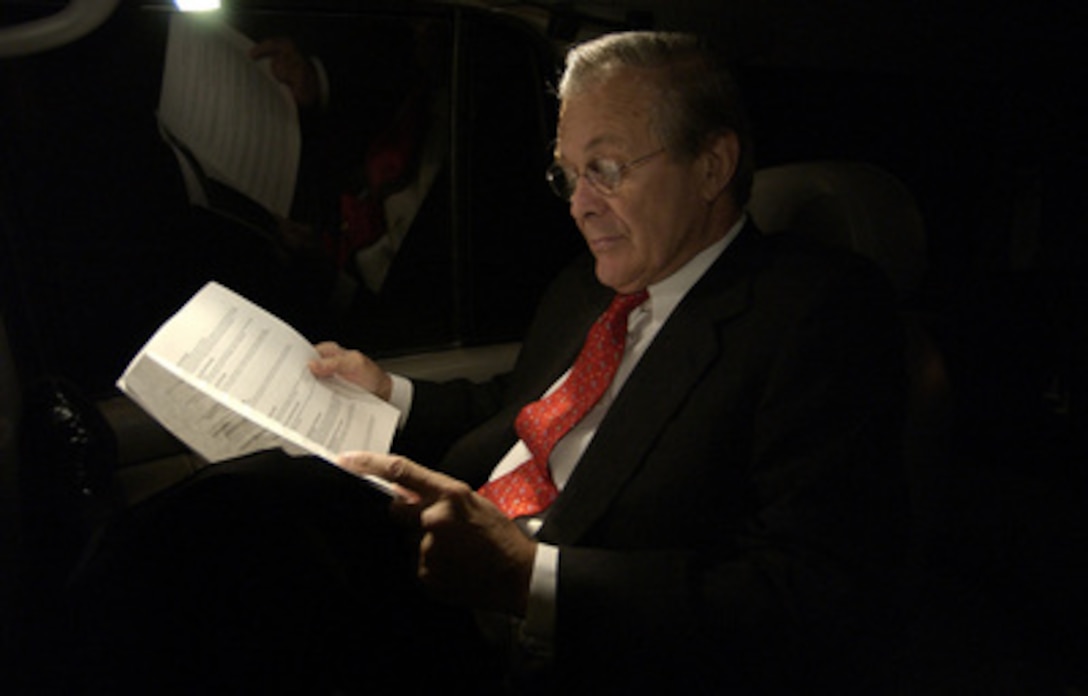 Secretary of Defense Donald H. Rumsfeld reviews pages of consolidated news reports during his ride to his office in the Pentagon on Oct. 2, 2003. 