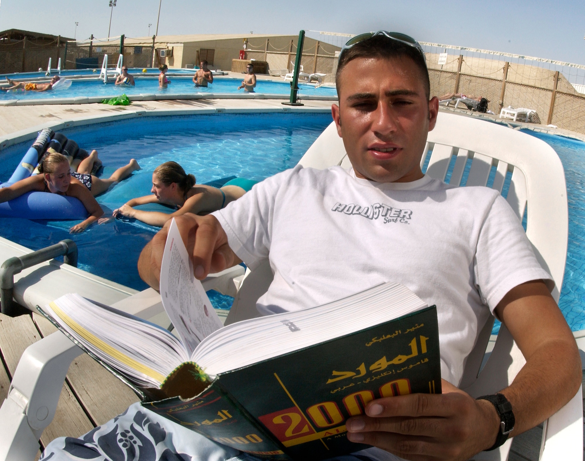 SOUTHWEST ASIA -- Airman 1st Class Ramin Amely sits poolside and reads a Farsi-English dictionary at an undisclosed desert location.  He is assigned to the 380th Expeditionary Security Forces Squadron.  His language skills help his unit work with host-nation patrols to guard the base.  (U.S. Air Force photo by Master Sgt. Lance Cheung)