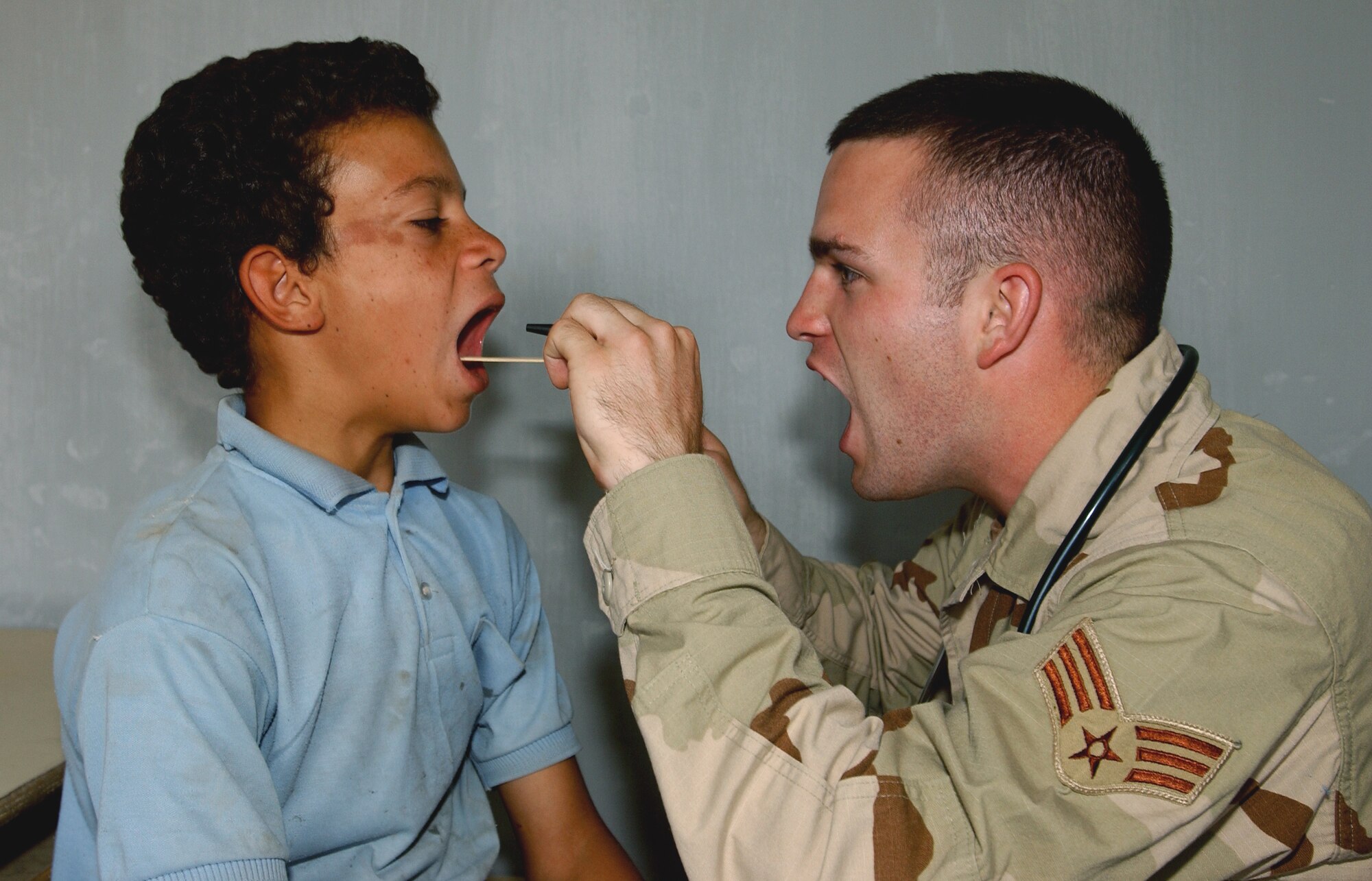 SWABE, Iraq -- Senior Airman Matthew Read convinces his patient to open wide here during a medical and humanitarian assistance mission.  Read is deployed with the 101st Expeditionary Rescue Squadron from the Air National Guard's 122nd Medical Group, in Fort Wayne, Ind.  (U.S. Air Force photo by Master Sgt. Robert R. Hargreaves Jr.)