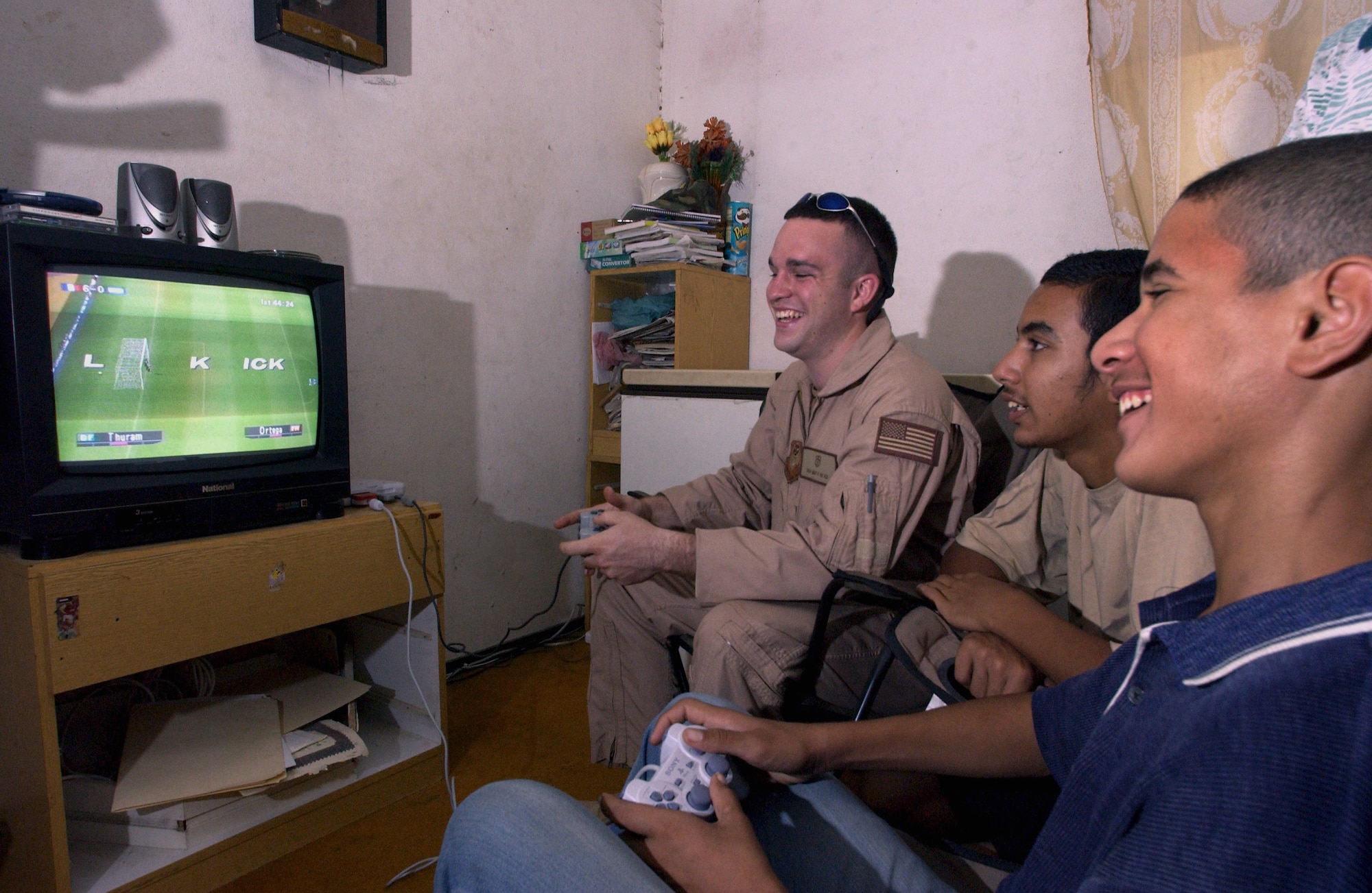 FRENCH VILLAGE, Iraq -- Senior Airman Matt Read (left) plays a Sony Play Station soccer game with 15-year-old Ahmed (right) and his brother Kaffar.  Ahmed beat Read, 7-0.  Read readily agreed to a rematch the next time the medics come to the village.  The airman is a medical technician with the 447th Expeditionary Rescue Squadron.  (U.S. Air Force photo by Master Sgt. Keith Reed)