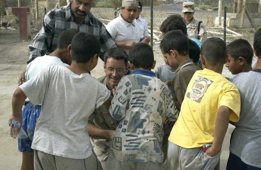 FRENCH VILLAGE, Iraq -- Maj. (Dr.) Gene Delaune shares candy and toys with children here.  Delaune is an individual mobilization augmentee deployed from the 89th Medical Group at Andrews Air Force Base, Md.  (U.S. Air Force photo by Master Sgt. Keith Reed)