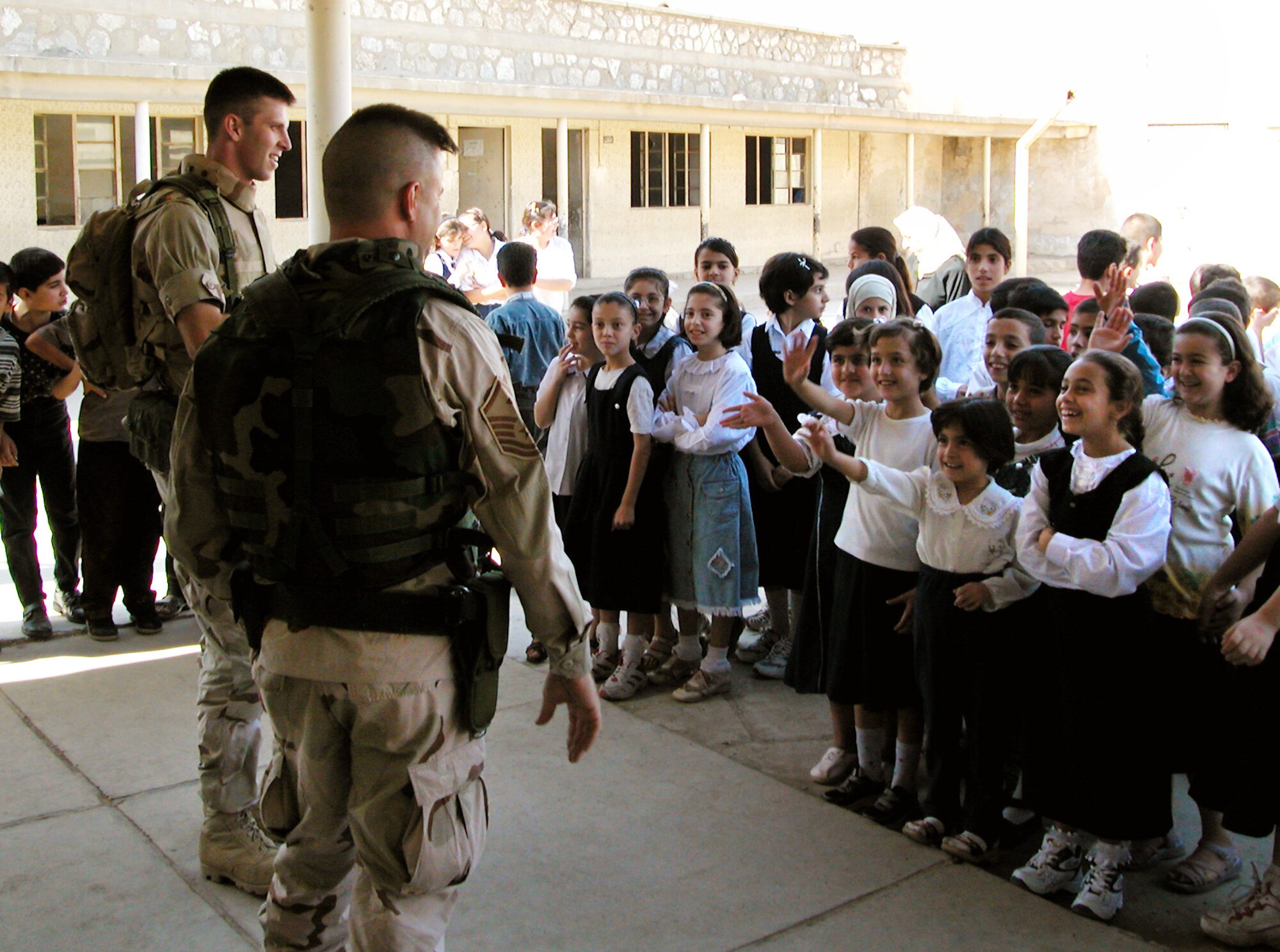 KIRKUK, Iraq -- Master Sgt. Robert Frank and 1st Lt. Art Patek talk with students at Al Ilaf school here.  The two were part of a team from the 380th Air Expeditionary Wing who traveled from a forward-deployed air base to donate more than $5,000 of supplies to schools here.  Frank is the first sergeant of the 380th Expeditionary Mission Support Group, and Patek is the 380th Expeditionary Operations Group executive officer.  (U.S. Air Force photo by Maj. Robert Couse-Baker)