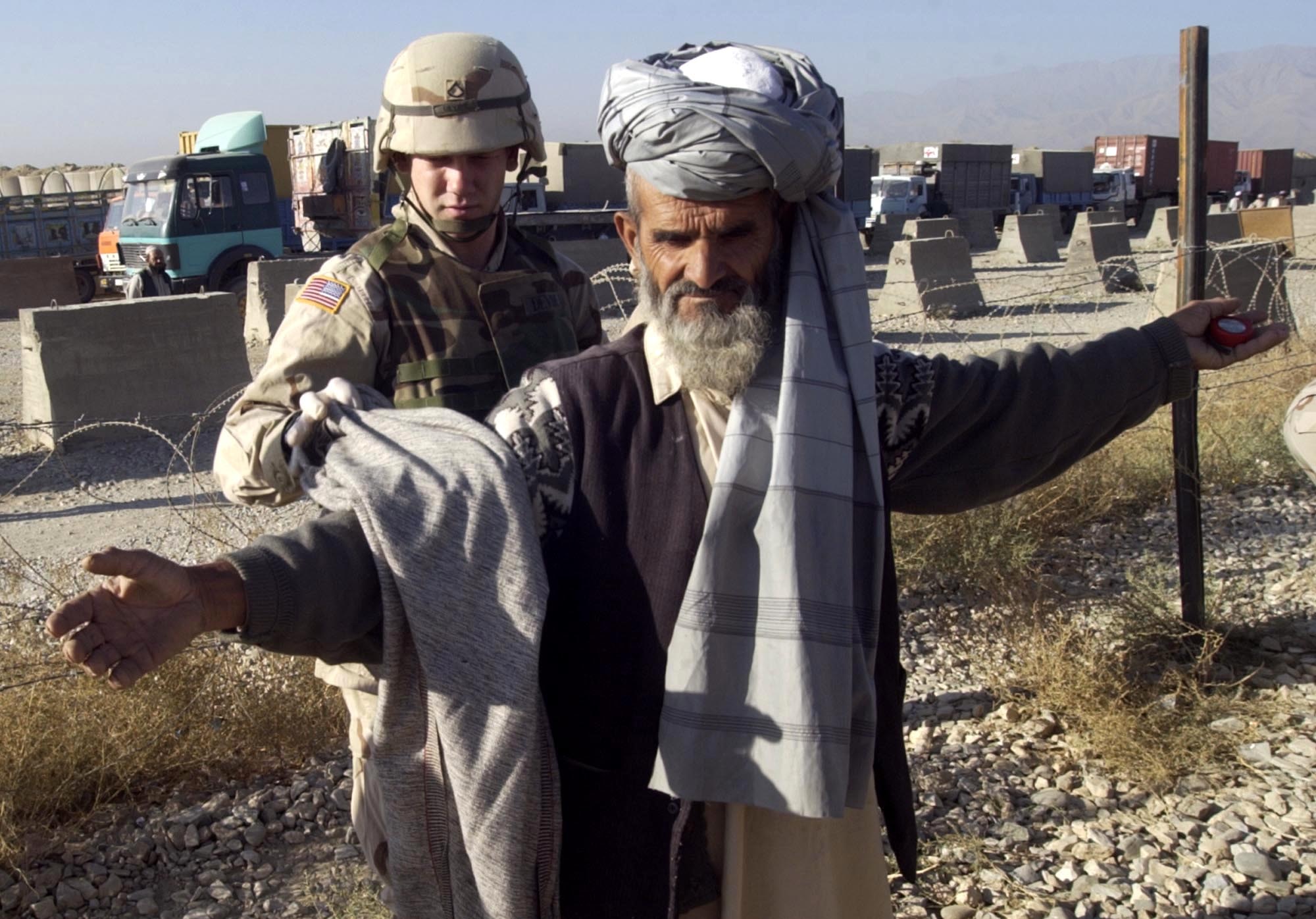 BAGRAM AIR BASE, Afghanistan -- Army Private 1st Class Matthew Devine checks a worker before he can access the installation.  Contracted workers erect huts and perform other duties.  They must be frisked, screened and have all clothing checked for weapons or other harmful materials.  (U.S. Air Force photo by Staff Sgt. Russell Wicke)