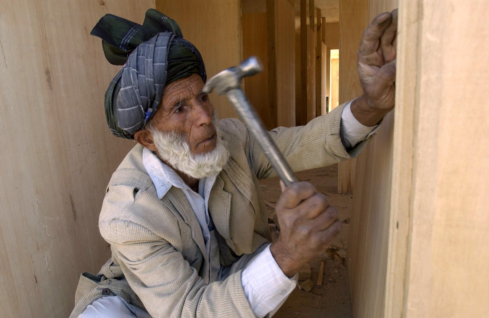 BAGRAM AIR BASE, Afghanistan -- A worker here hammers a nail inside a B-hut at Air Force Village.  Afghan carpenters construct these huts using only hand tools.  Even sheets of plywood are cut by hand. The huts will replace the temper tents as living quarters.  (U.S. Air Force photo by Master Sgt. Lance Cheung)