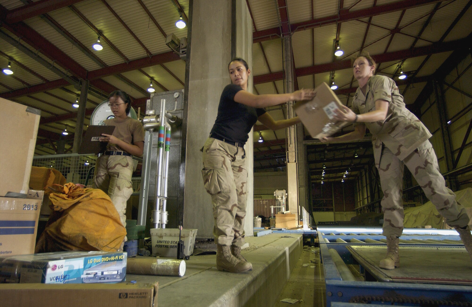 BAGHDAD INTERNATIONAL AIRPORT, Iraq -- Airman 1st Class Christine Mayor, Senior Airman Alaine Wallace and Capt. Denise Freimuth load mail onto pallets in 100-plus degree temperatures.  The 447th Expeditionary Communications Squadron team handles more than 150,000 pounds of mail flowing to and from air post offices at American camps in Iraq every day.  (U.S. Air Force photo by Master Sgt. Keith Reed)