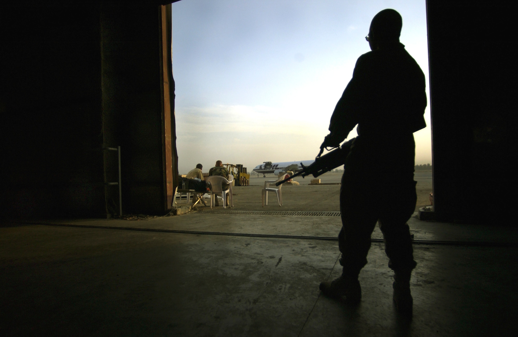 BAGHDAD INTERNATIONAL AIRPORT, Iraq -- A 1st Armored Divison soldier protects Air Force mail handlers here.  The airmen handle more than 150,000 pounds of mail flowing to and from air post offices at American camps in Iraq every day.  (U.S. Air Force photo by Master Sgt. Keith Reed)
