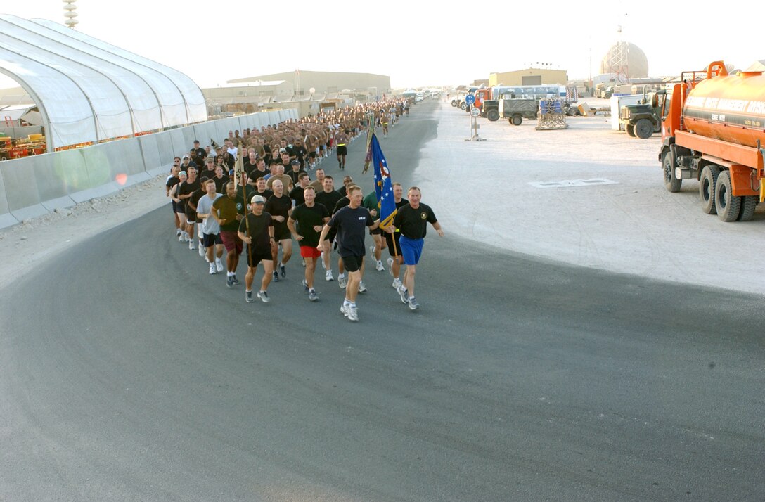 SOUTHWEST ASIA -- Chief Master Sgt. Richard Small (left) and Col. Jack Egginton carry the Air Force flag during a fitness run at a forward-deployed location Oct. 29.  More than 600 airmen from the 379th Air Expeditionary Wing participated.  The run was a show of support for the new Air Force fitness standards.  Small is the wing's command chief master sergeant, and Egginton is its commander.  (U.S. Air Force photo by Staff Sgt. Dawn Finniss)

