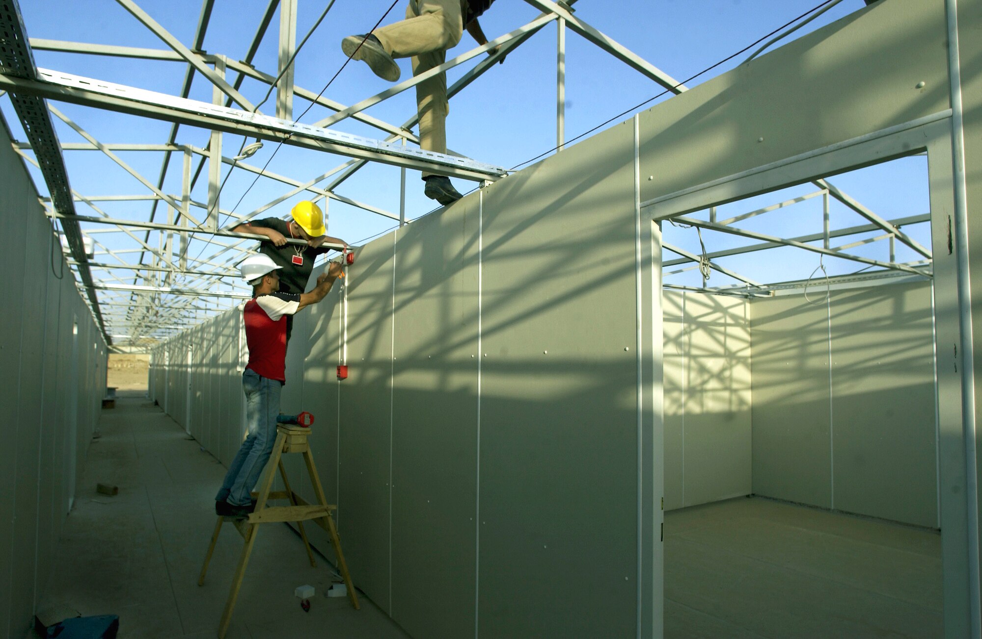 KIRKUK AIR BASE, Iraq -- Contractors install fire alarms into new dormitories which are scheduled to open Dec. 1.  The buildings will house up to 1,664 airmen in 13 buildings with six to eight people per room.  The construction crews are averaging two buildings completed every three days since they began Sept. 23.  (U.S. Air Force photo by Master Sgt. Keith Reed)