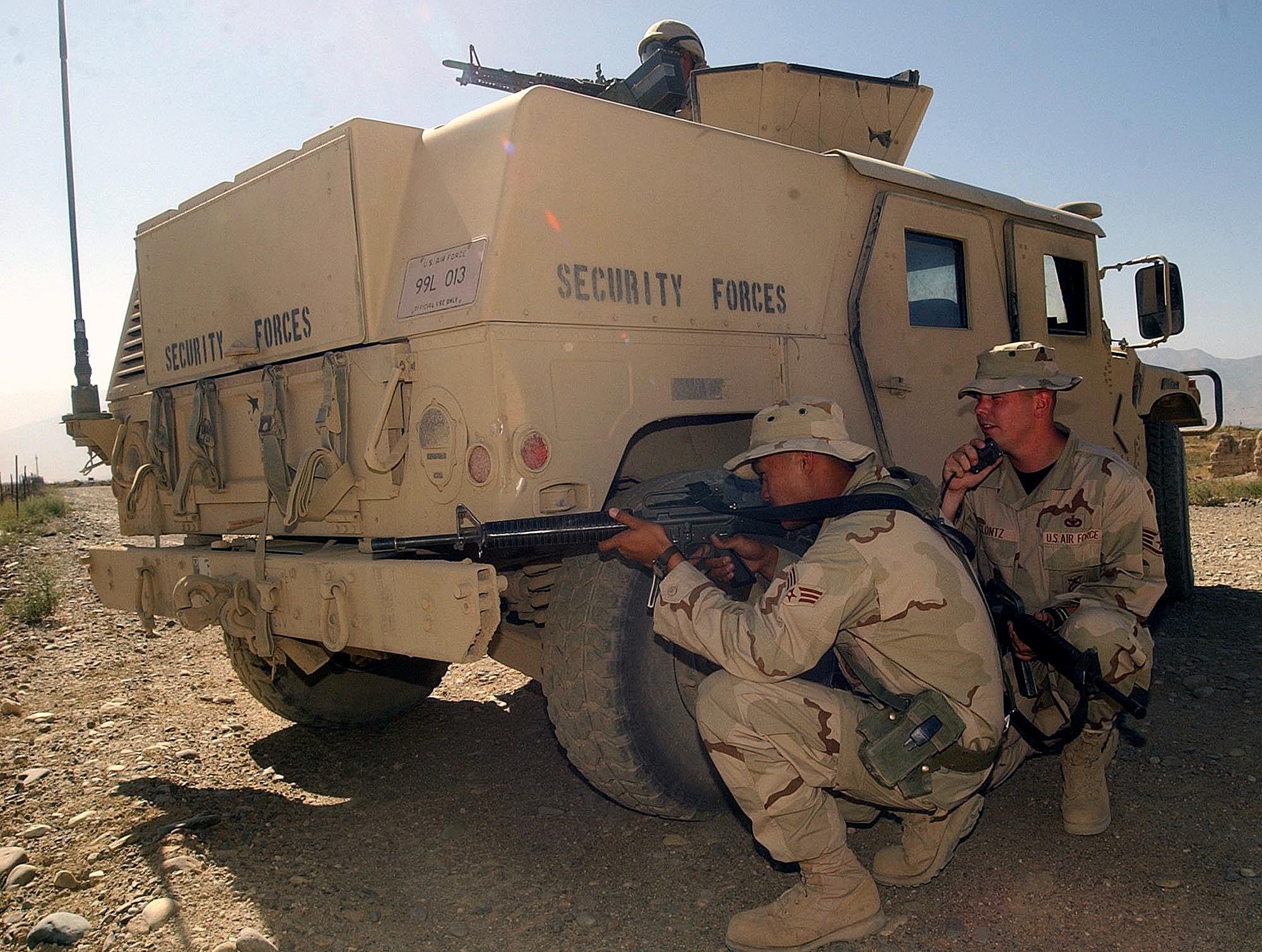 BAGRAM AIR BASE, Afghanistan -- Senior Airman Zane Aguilar (left) practices a defensive posture behind an armored Humvee as Staff Sgt. Alan Clontz calls in on the radio.  The airmen are assigned to the 455th Expeditionary Security Forces Squadron here.  Hostile encounters are likely on the perimeter of the base here.  Air Force security forces work with the Army to secure the base.  (U.S. Air Force photo by Staff Sgt. Russell Wicke)