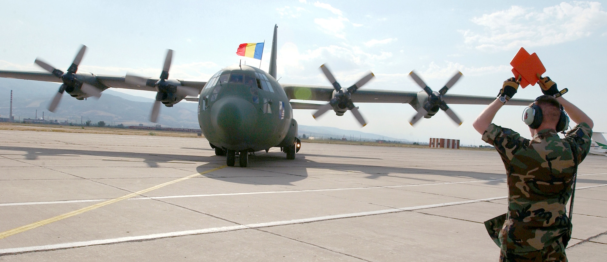 PLOVDIV, Bulgaria -- Staff Sgt. Justin Neiderhofer marshalls a Romanian C-130 cargo aircraft at Krumovo Airport here Sept. 1 as part of Cooperative Key 2003.  Neiderhofer is a crew chief assigned to the 86th Air Mobility Squadron deployed from Ramstein Air Base, Germany.  Cooperative Key is a multinational exercise designed to enhance the interoperability of NATO and partner nation air forces through cooperation and familiarization of the organization's procedures.  (U.S. Air Force photo by Staff Sgt. Marie Cassetty)