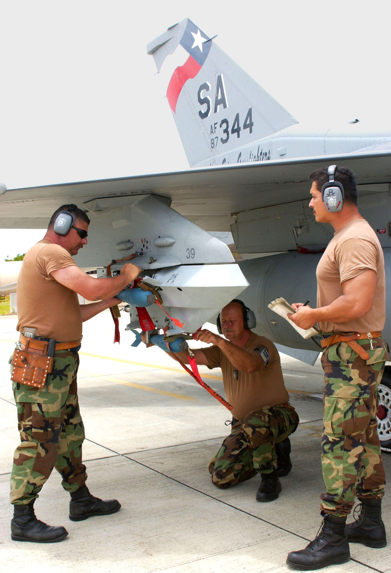 HICKAM AIR FORCE BASE, Hawaii -- A 149th Fighter Wing weapons load team secures BDU-33 bombs to an F-16 Fighting Falcon.  The team consists of (from left) Staff Sgts. Donald Trevathan and John Schoonover, and Tech. Sgt. Roy Garza.  The aircraft were being readied with the practice bombs for close-air-support training with soldiers. (U.S. Air Force photo by Senior Master Sgt. Mike Arellano)