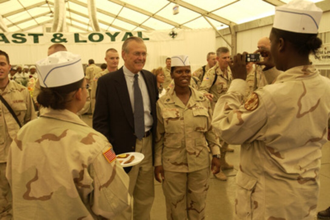 Secretary of Defense Donald H. Rumsfeld poses for a photo with a member of the 4th Infantry Division before sitting down to lunch with the troops in Tikrit, Iraq, on Sept. 5, 2003. 