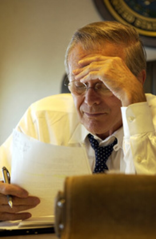 Secretary of Defense Donald Rumsfeld catches up on paperwork while en route to Iraq and Afghanistan on Sept. 3, 2003. 