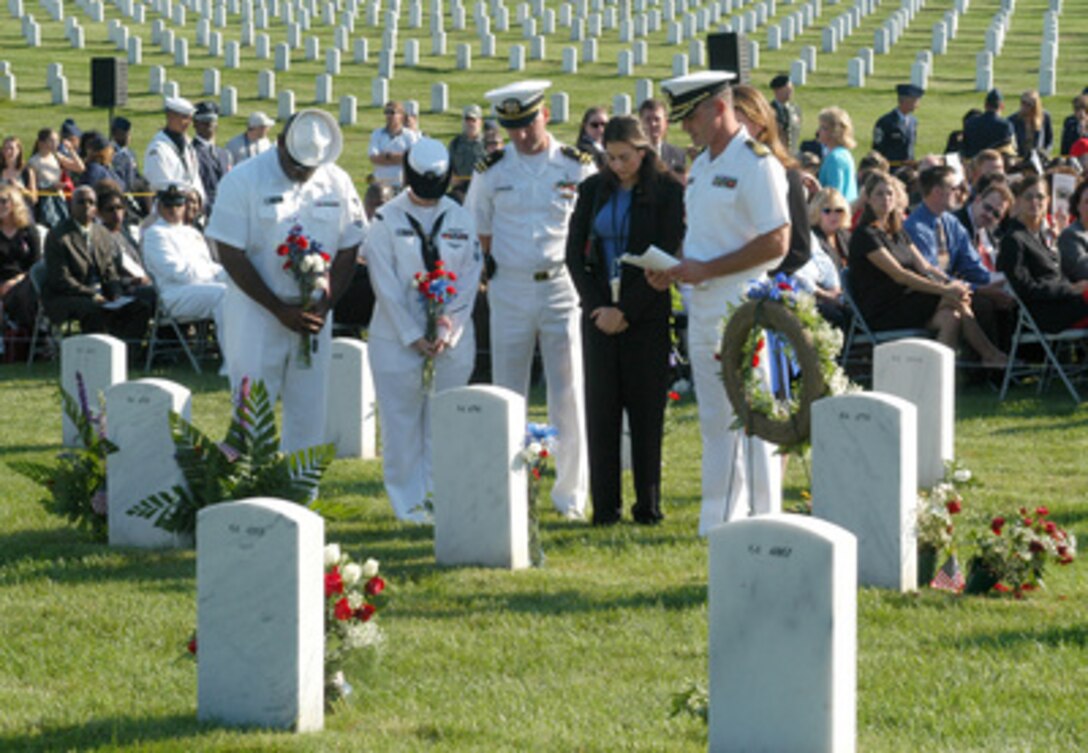 A group of U.S. Navy personnel pray at the grave of a comrade lost in the September 11, 2001, terrorist attack on the Pentagon. Many families and friends of the victims were on hand for the Sept. 11, 2003, memorial wreath laying performed at Arlington National Cemetery by Secretary of Defense Donald H. Rumsfeld and Chairman of the Joint Chiefs of Staff Gen. Richard B. Myers. Fifty of the victims of the attack are buried in this particular section containing a monument to all the victims. 