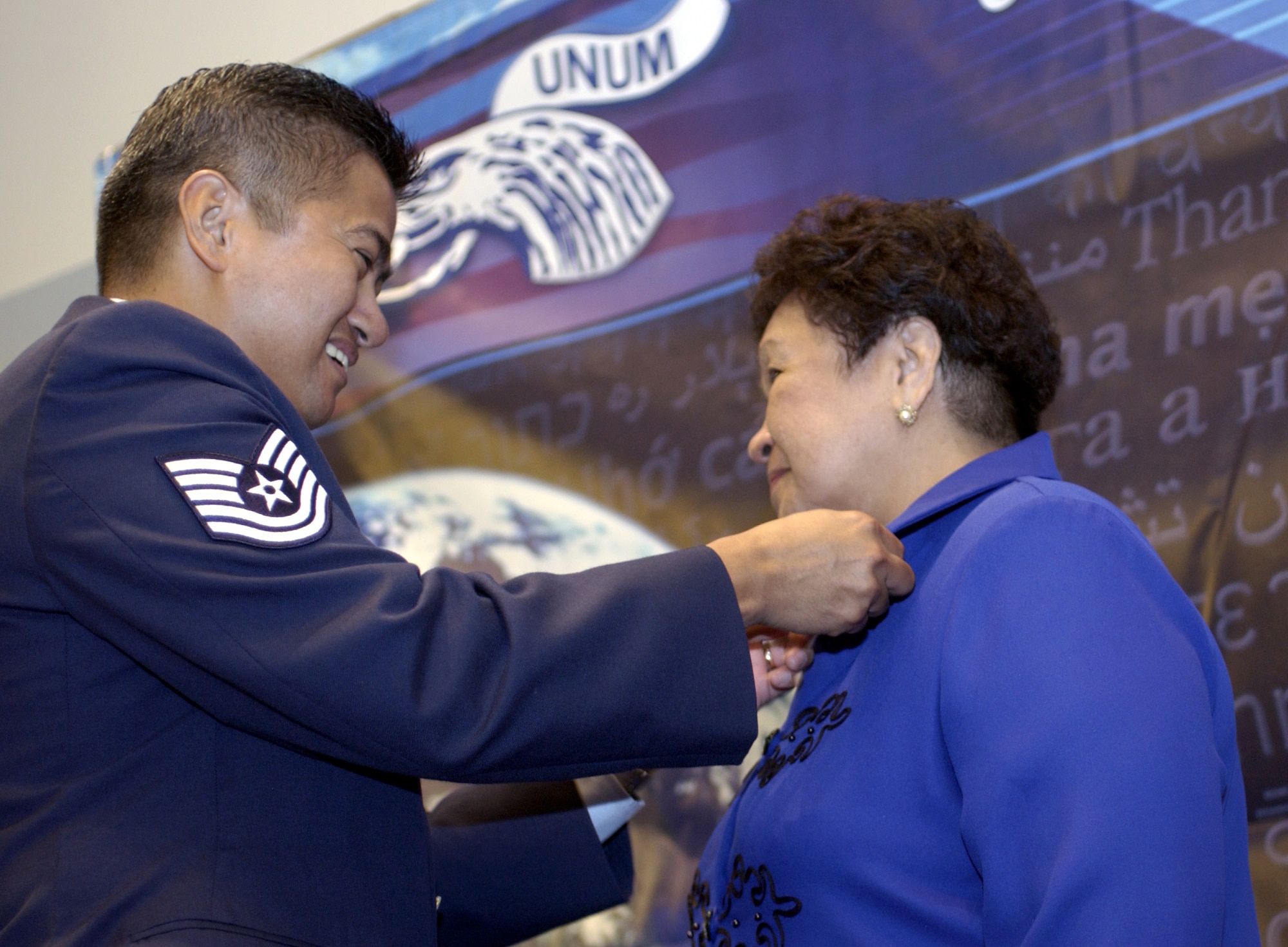 WASHINGTON -- Tech. Sgt. Ares Bisco pins a Parent Pin on his mom, Mila Bisco, during a ceremony launching "E Pluribus Unum," at the National Press Club here Sept. 12.  Bisco is a native of the Philippines and stationed in the Pentagon.  A letter written in Tagalog, her native tongue, accompanied the pin.  E Pluribus Unum is a diversity-outreach campaign thanking parents of airmen in 100 native languages.  Translated from Latin, it means, "out of many, one."  (U.S. Air Force photo by Master Sgt. Jim Varhegyi)