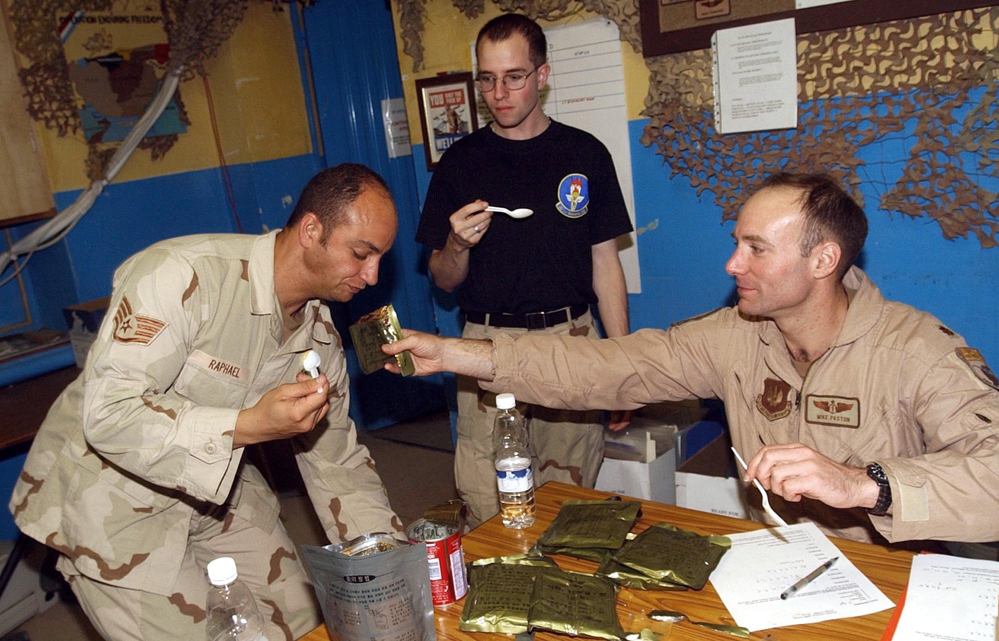BAGRAM AIR BASE, Afghanistan -- Maj. (Dr.) Michael Paston offers a Thai ration to Staff Sgt. Brian Raphael, who sniffs it skeptically, while Senior Airman Brian Miller waits his turn.  Their inputs about the ration will be recorded and used in Paston's research.  Paston, Raphael and Miller are assigned to the 455th Expeditionary Operations Group here.  (U.S. Air Force photo by Staff Sgt. Russell Wicke)