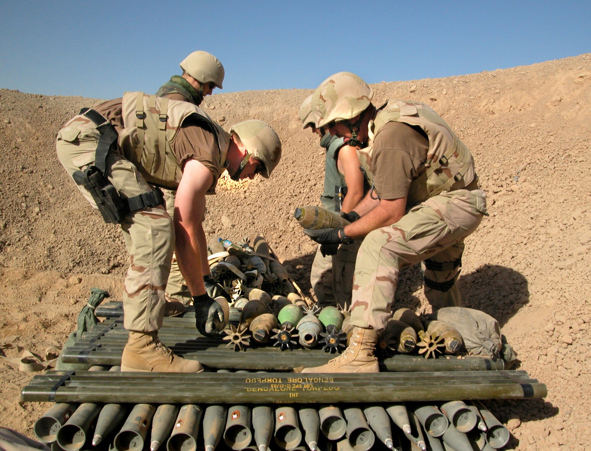 KIRKUK, Iraq -- Staff Sgt. Justin Alonzo (left) and Master Sgt. Dale Griffin work with explosive ordnance disposal technicians from Latvia to prepare Iraqi high-explosive mortar shells, Bangalore torpedoes and 122 mm surface-to-surface rockets for demolition.  Alonzo and Griffin are EOD technicians deployed to nearby Kirkuk Air Base.  (U.S. Air Force photo by Maj. Robert Couse-Baker)