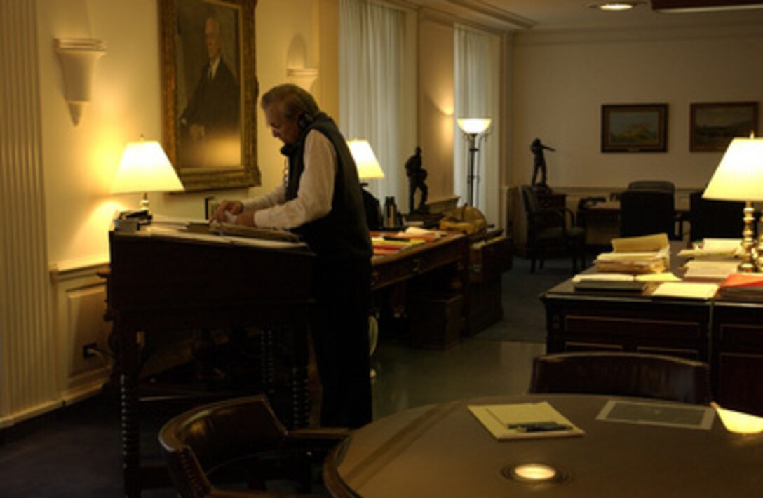 Secretary of Defense Donald H. Rumsfeld works at his desk and talks on the phone while in his office at the Pentagon on Sept. 11, 2003. 