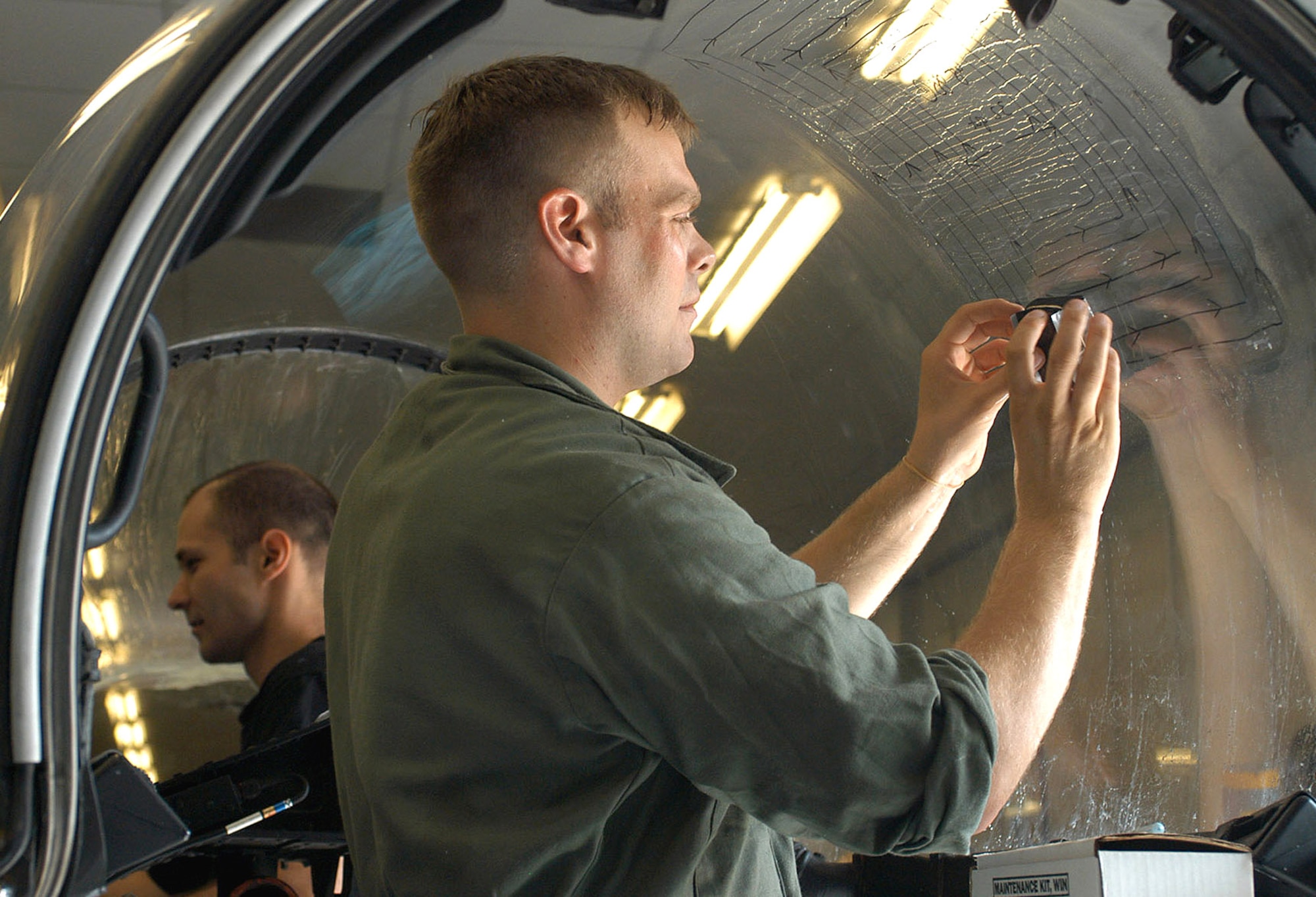 ROYAL AIR FORCE LAKENHEATH, England (AFPN) -- Senior Airman Chad Ausbrooks (foreground) and Tech. Sgt. James Niece sand a canopy in the structural maintenance shop here.  Ausbrooks is an aircraft structural maintenance journeyman and Niece is a maintenance apprentice.  Both are assigned to the 48th Equipment Maintenance Squadron.  (U.S. Air Force photo by 1st Lt. Ed Ekpoudom)