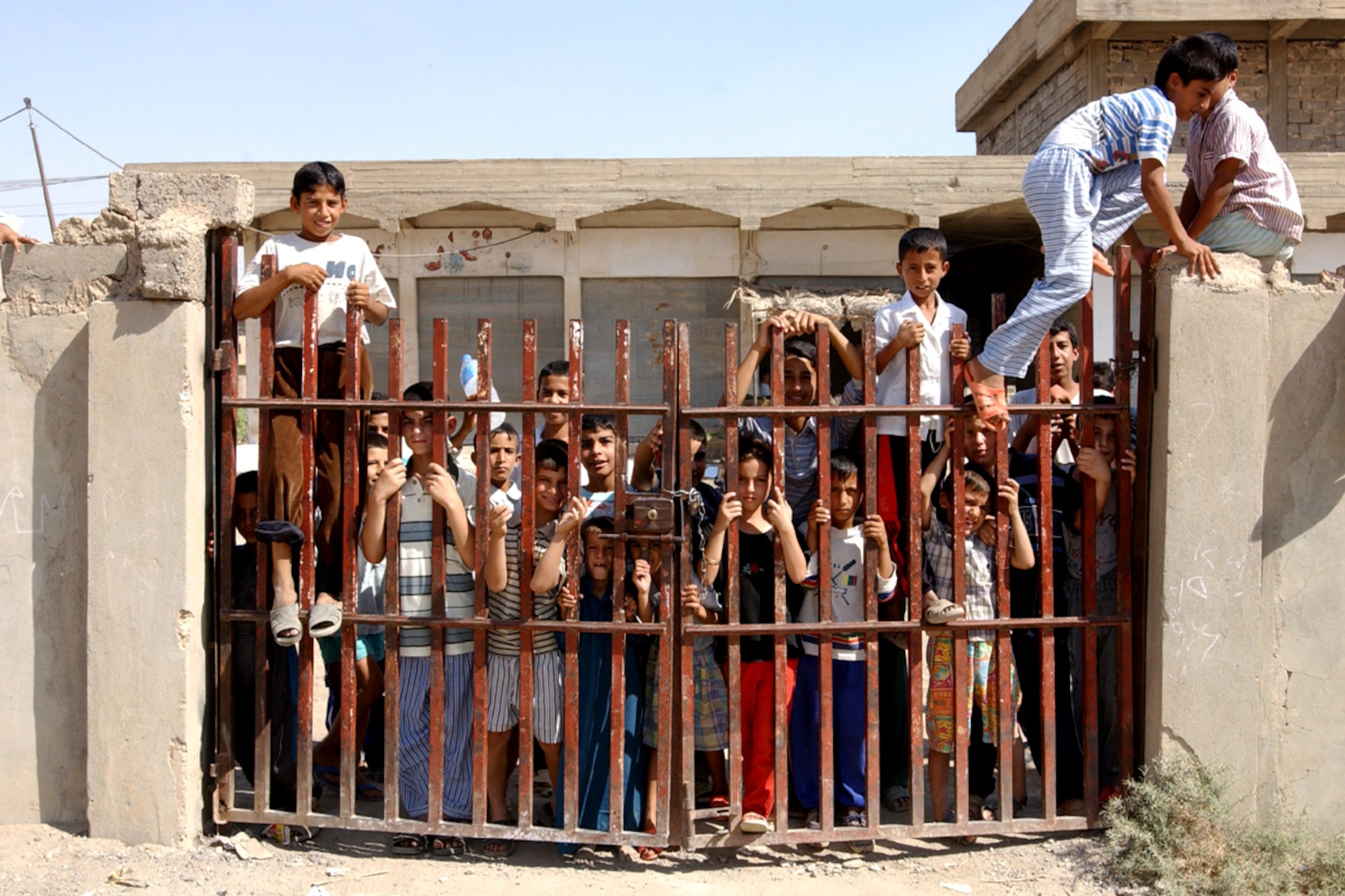 KIRKUK, Iraq (AFPN) -- Iraqi students wait impatiently at the gates for the opening of their new school.  Army and Air Force troops volunteered to renovate two local schools near Kirkuk Air Base, Iraq.  (U.S Air Force photo by Tech. Sgt. Charlein She)