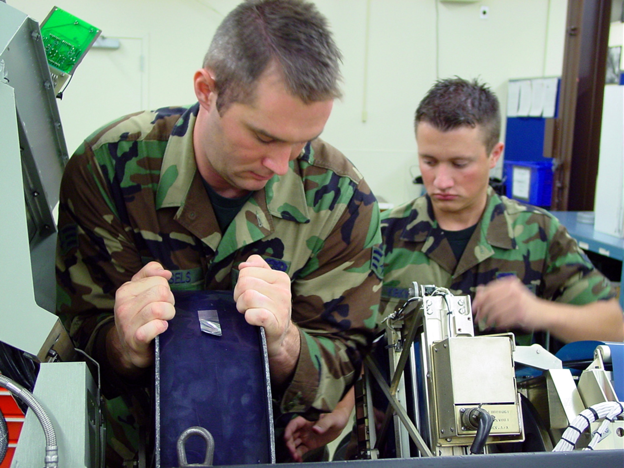 BEALE AIR FORCE BASE, Calif. (AFPN) -- Senior Airman Martin Vessels (left) loads a 100-pound roll of film into a U-2 optical bar camera.  Airman 1st Class Derek Kirkwood (right) delivered the film.  Both are 9th Maintenance Squadron avionics sensor technicians assigned here.  (U.S. Air Force photo by Master Sgt. Tim Helton)