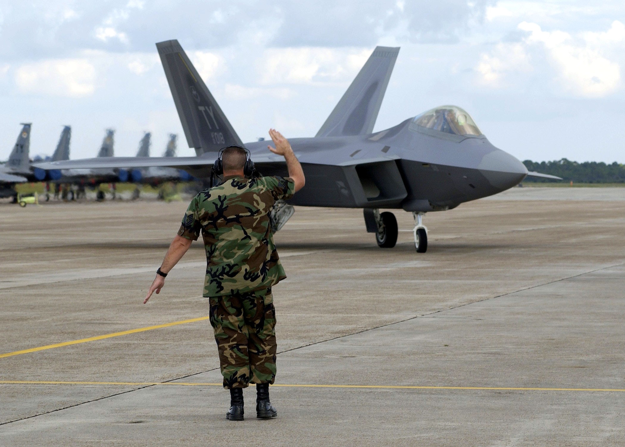 TYNDALL AIR FORCE BASE, Fla. -- Tech. Sgt. Jeff Simpson guides Raptor number 18 to its parking spot. Raptor 18 is the first operational F/A-22 Raptor delivered to the Air Force’s F/A-22 schoolhouse here. The Raptor will eventually replace the F-15 Eagle and sets the foundation for the next generation of combat-fighter pilots. (U.S. Air Force photo by Steve Wallace)

