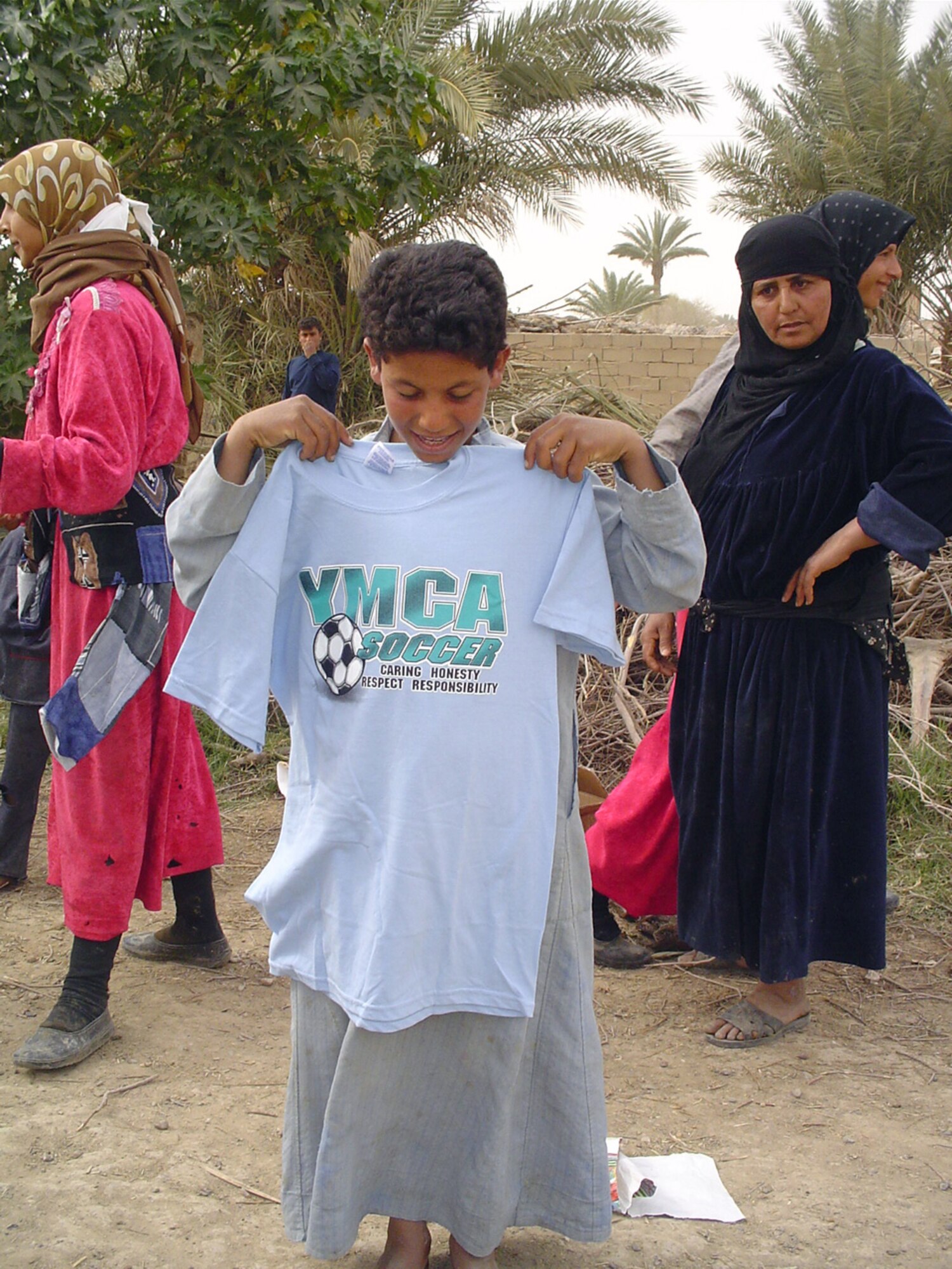 VEDGHA, Iraq - A young Iraqi admires his new shirt after a team from the 447th Air Expeditionary Group at Baghdad International Airport distributed clothing, shoes, food, toys and medication here recently.  Team' from the group conduct the humanitarian-relief missions about once a month.  (U.S. Air Force photo by Master Sgt. Sean E. Cobb)
