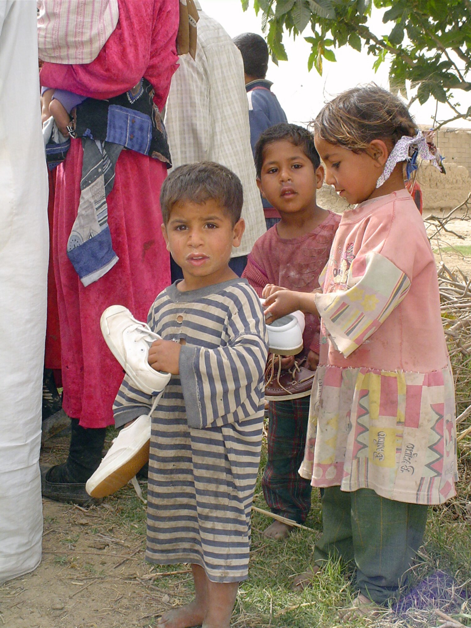 VEDGHA, Iraq - Iraqi children are not quite sure what to do with the shoes they were given during a recent humanitarian relief mission here.  Airmen of the 447th Air Expeditionary Group at Baghdad International Airport were here handing out donated goods donated from their home bases.  (U.S. Air Force photo by Master Sgt. Sean E. Cobb)