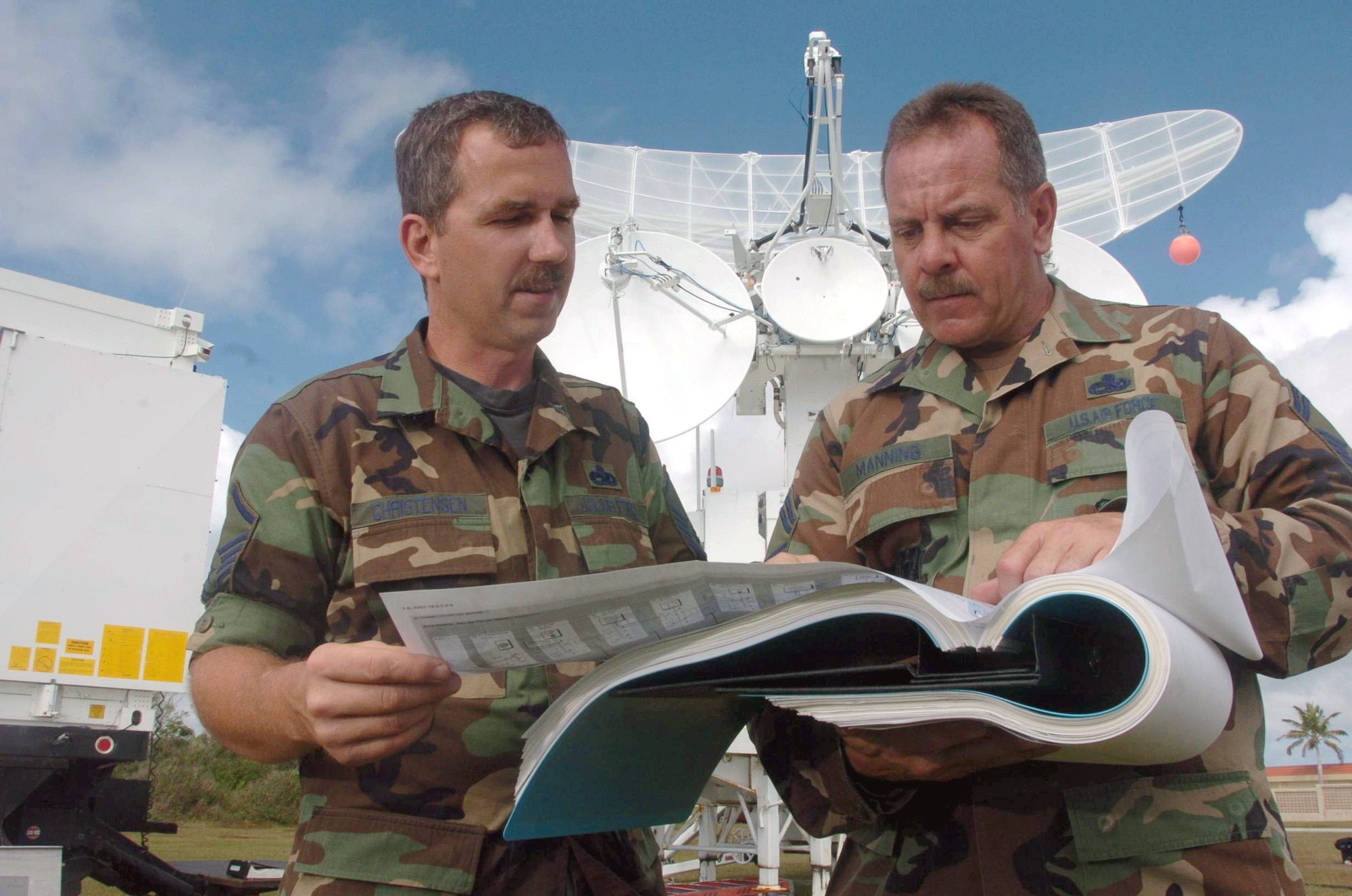 ANDERSEN AIR FORCE, Guam -- Senior Master Sgt. Mike Manning (right) and Master Sgt. Patrick Christensen use a manual to calibrate a Multiple Threat Emitter System here.  The system is a computer-controlled, multiple emitter system designed to transmit simulated threat signals.  Both sergeants are radar maintainers from the 266th Range Squadron at Mountain Home Air Force Base, Idaho.  (U.S. Air Force photo by Master Sgt. Val Gempis)