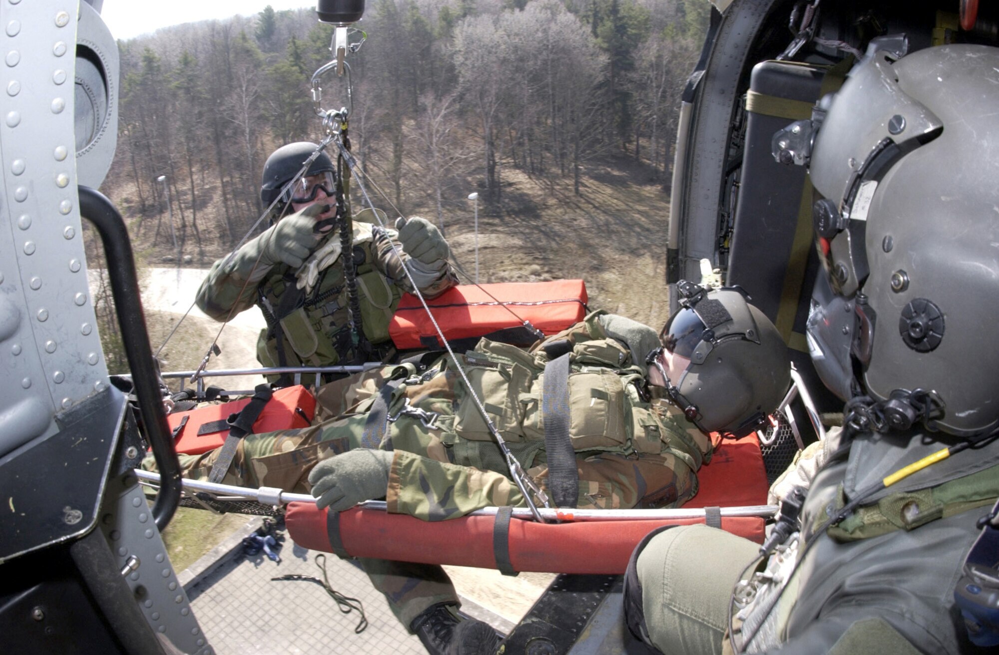 HOHENFELS ARMY AIR FIELD, Germany -- Tech. Sgt. Brian Tharp stabilizes the litter as the "patient," Army Specialist James Fitch, is hoisted into an HH-60G Pave Hawk here March 31.  Sergeant Tharp is a pararescue Airman from the 56th Rescue Squadron.  Specialist Fitch is from the 236th Medical Company at Landstuhl, Germany.  They are participating in a joint combat search and rescue exercise.  (U.S. Air Force photo by Staff Sgt. Edward Braly)