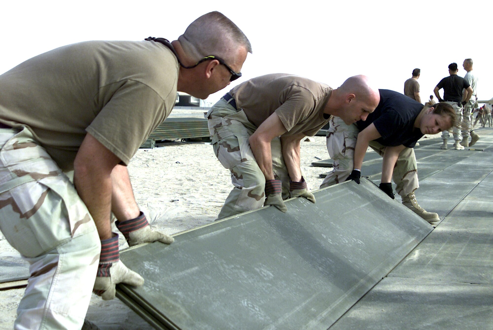 SOUTHWEST ASIA -- Airmen from the 386th Air Expeditionary Wing install planks for the new 320,000-square-foot C-130 Hercules parking ramp.  The planks were made out of interlocking aluminum matting.  (Courtesy photo)